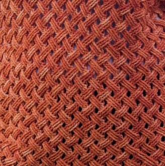 Close-up of Creative Sparks Woven Cables Crochet with a textured, interlocking basket-like pattern in warm earthy tones of orange and brown, similar to advanced techniques from crochet courses, crafting a complex and visually interesting surface.