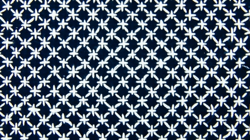 Close-up of the "Rice Stitch: Hitomezashi (Sashiko Starter Series #1)" by Creative Spark, showcasing a repeating geometric pattern of white star-like shapes on dark blue, inspired by traditional sashiko embroidery.