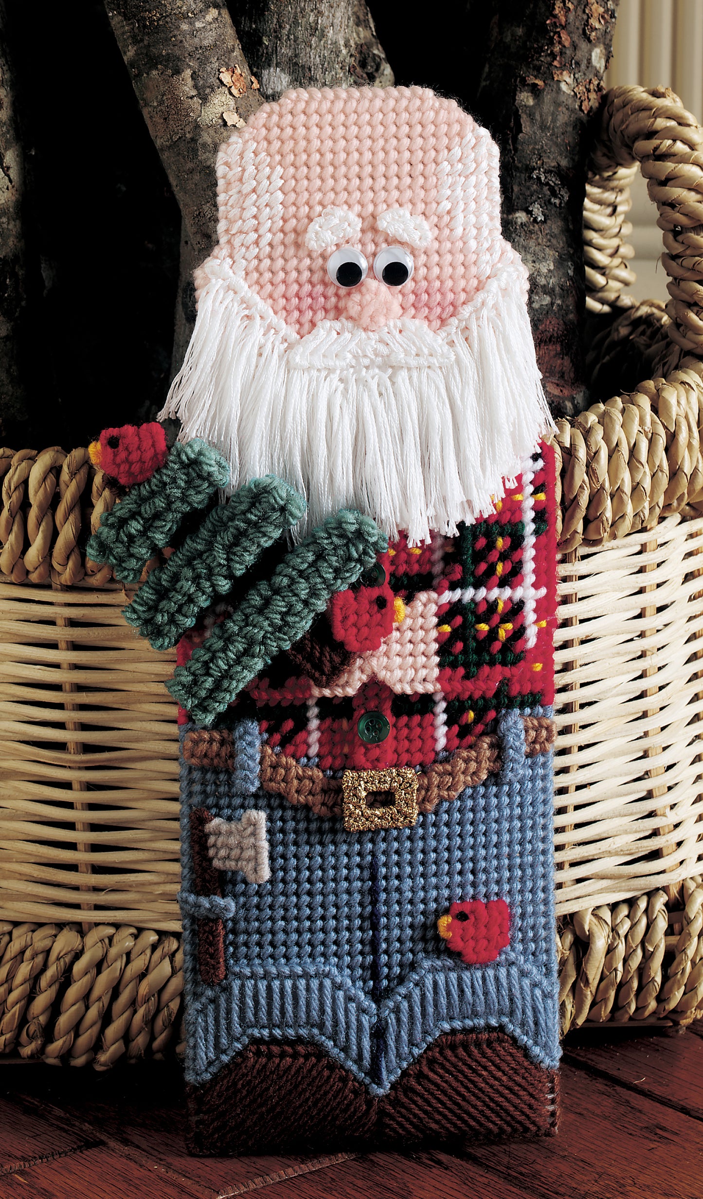 Leisure Arts’ Santa Line-Ups in Plastic Canvas Digital Download is a handmade figure featuring a white beard, pink face, red/green sweater, blue pants, and buttons, standing by a log-filled basket—perfect for beginner crafters.