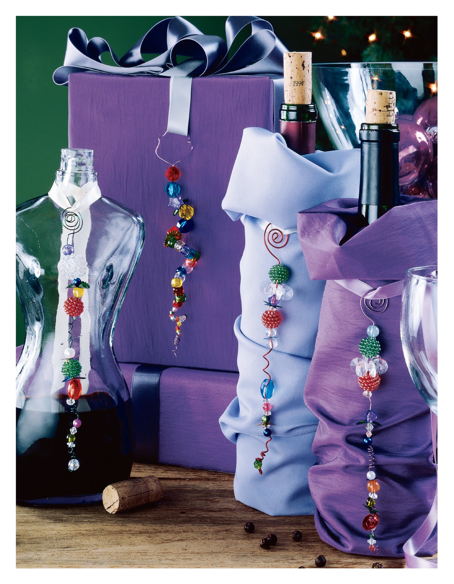 Purple gift boxes and wine bottles with beaded charms, inspired by the Leisure Arts Big Book of Beaded Ornaments, are perfect for festive family crafts. A wine glass and cork add elegance to this charming holiday scene.