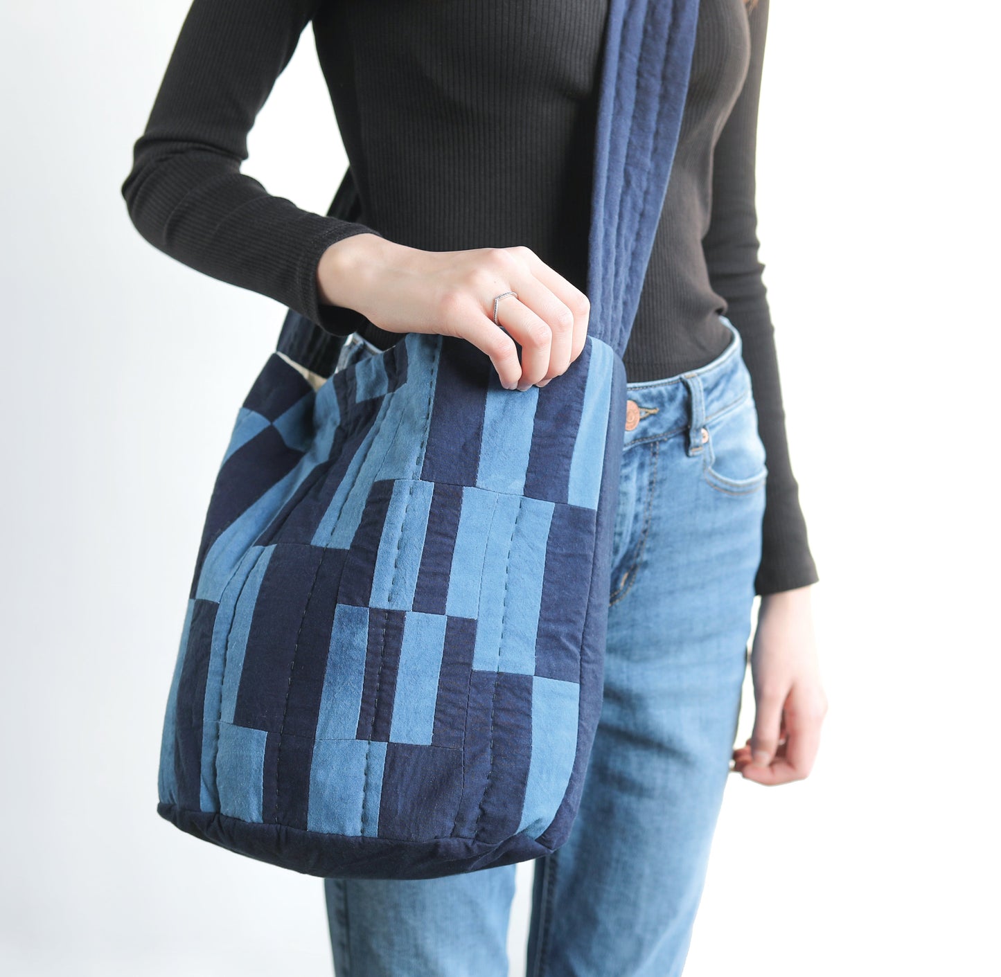 A woman holds the "Contemporary Patchwork" bag by Stash Books, showcasing unique surface design techniques in blue and black.