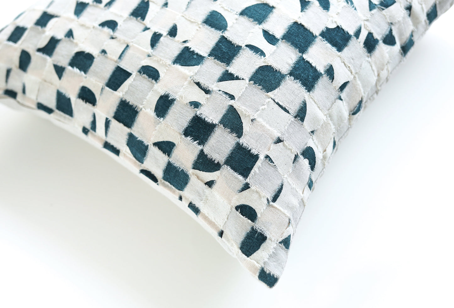 A close-up of the "Contemporary Patchwork" pillow by Stash Books features a textured surface and blue and white geometric circles and squares on a white background, angled on a plain white surface.