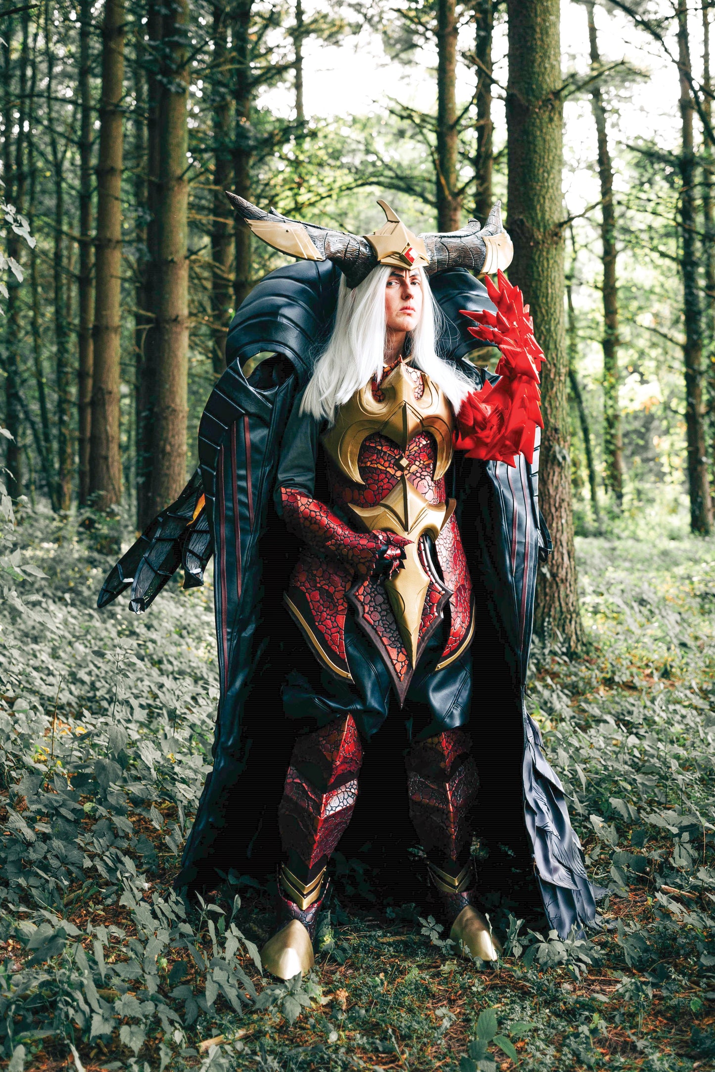 Inspired by The Ultimate Glue Guide Digital Download from FanPowered Press, a cosplayer in a fantasy warrior costume—horns, red and black armor, white hair, clawed gauntlet—stands in a forest after using tips for gluing different materials to create the detailed look.