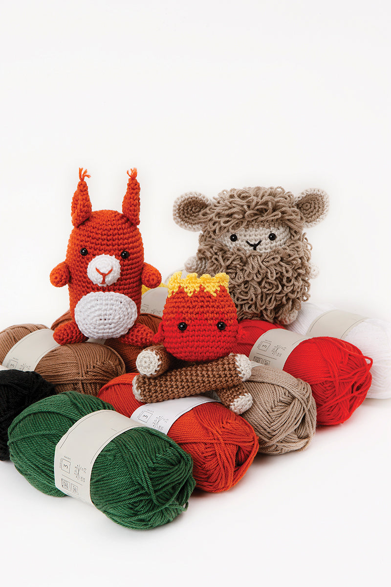 Three colorful crochet animals with yarn balls on a white background