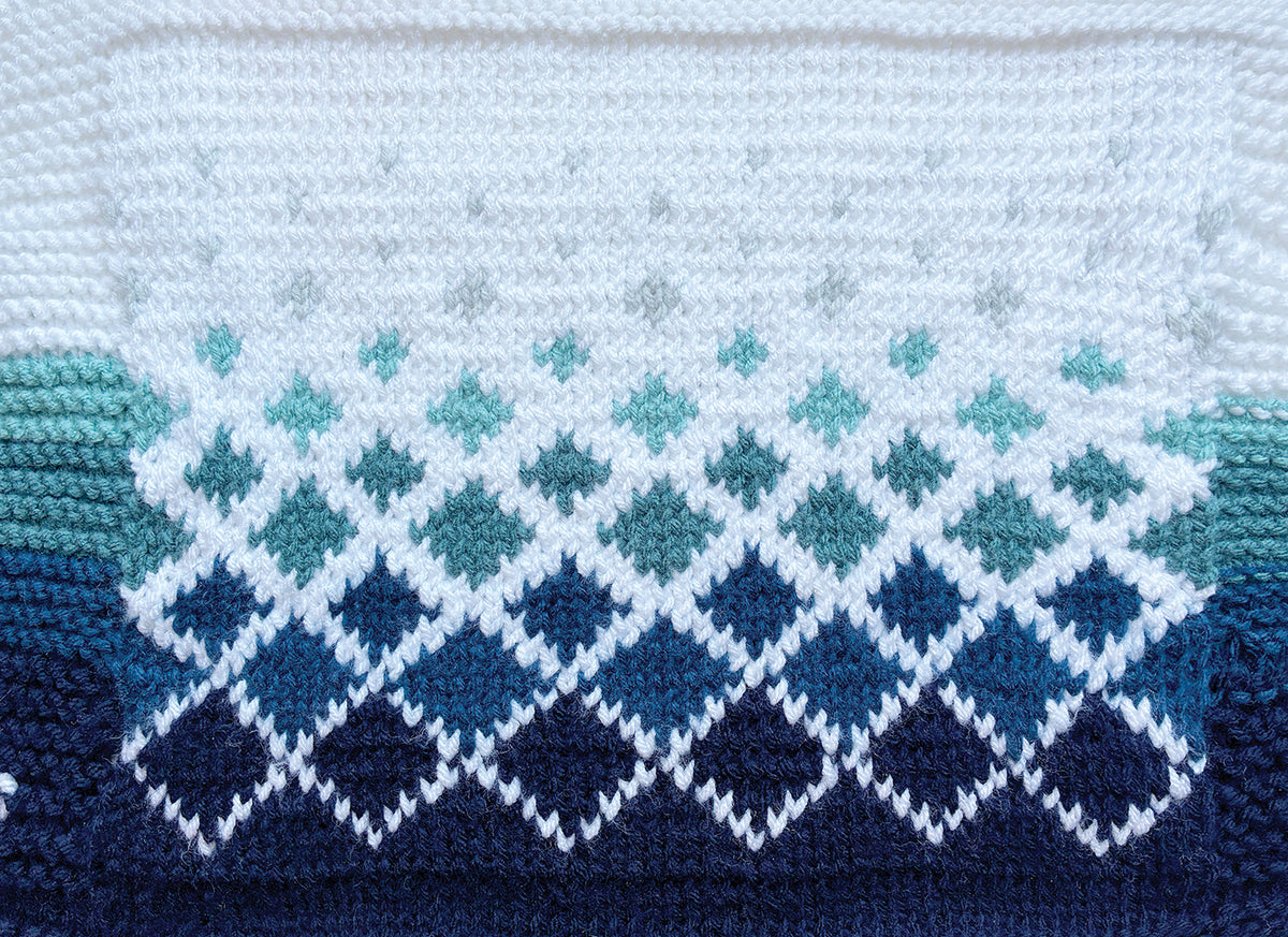 Close-up of knitted diamond fabric in white, teal, and blue, fading from white to dark blue. The Yarn Art Project Tote by C&T Publishing shows off visible yarn and stitches—ideal texture for your next craft project.