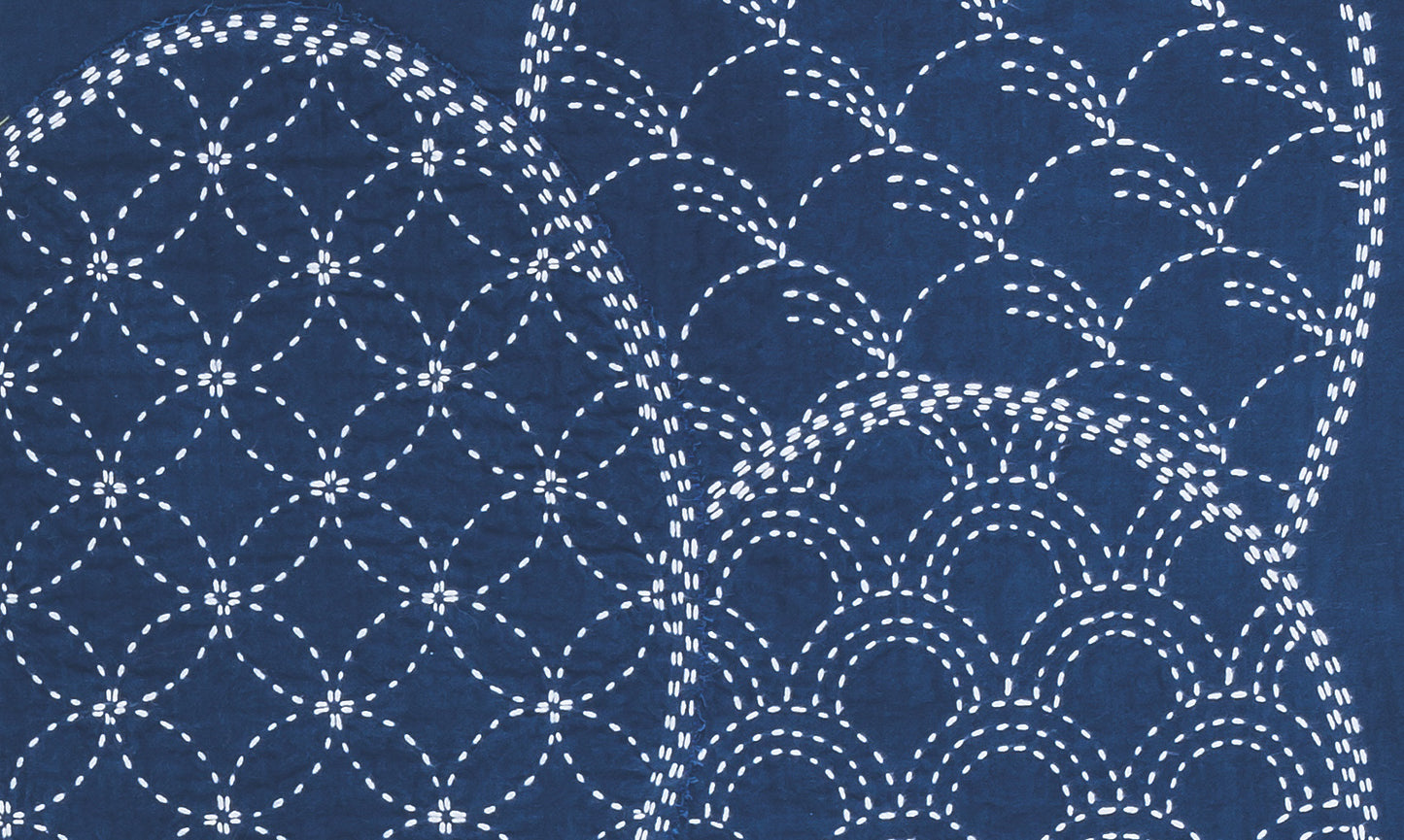 White dashed lines form overlapping circles and waves on dark blue, echoing traditional Sashiko embroidery. Inspired by Sashiko 101: Iconic First Stitches from Creative Spark, these precise patterns feature geometric and curved stitch designs.