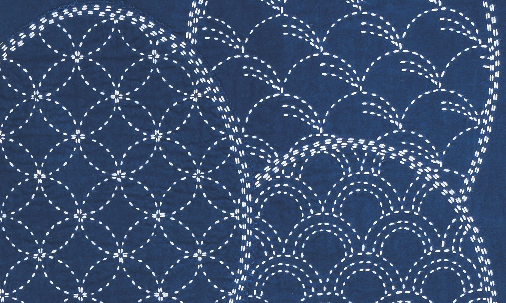 White dashed lines form overlapping circles and waves on dark blue, echoing traditional Sashiko embroidery. Inspired by Sashiko 101: Iconic First Stitches from Creative Spark, these precise patterns feature geometric and curved stitch designs.