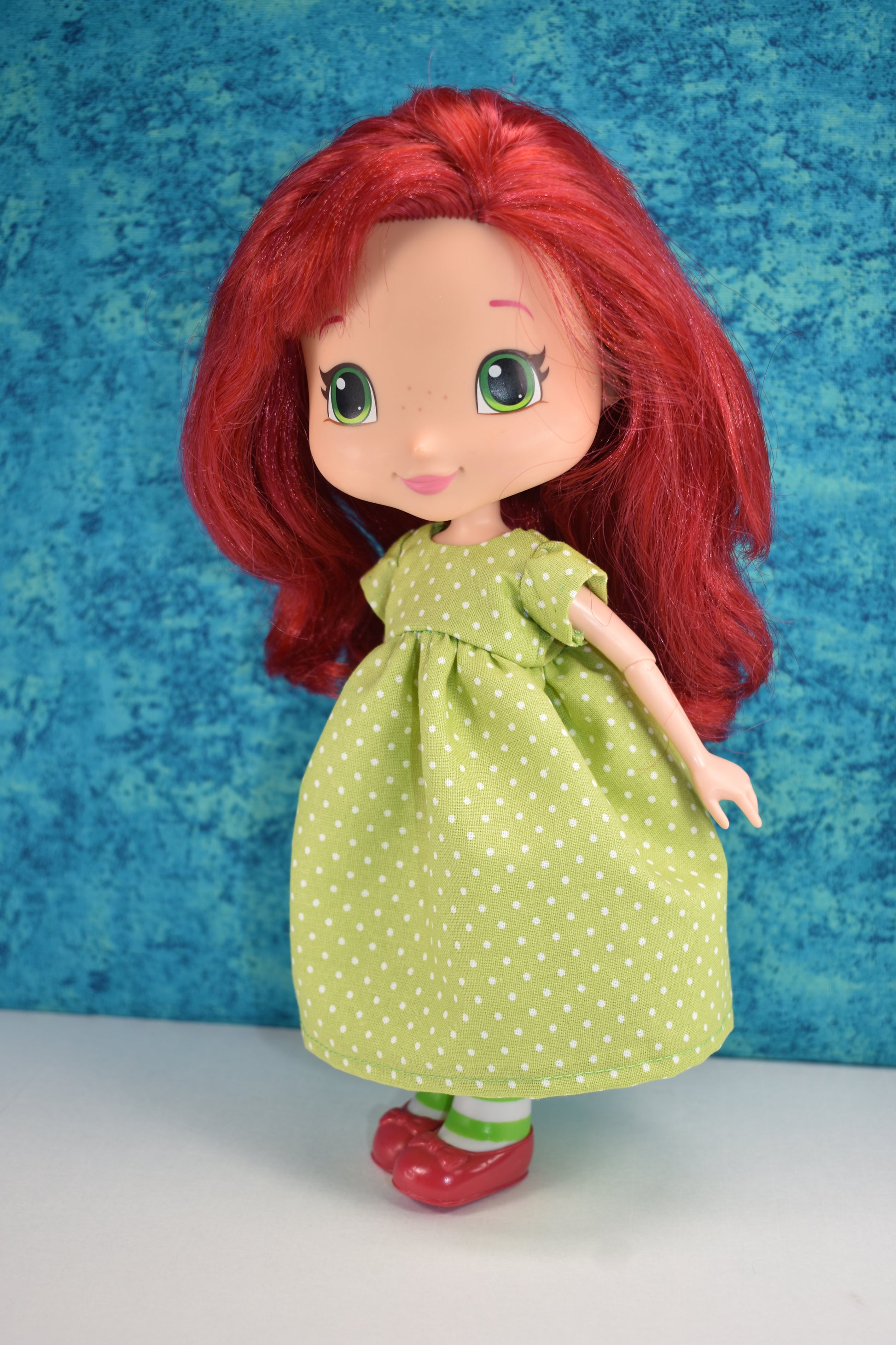 Creative Spark’s “How to Alter Doll Clothes Patterns” is perfect for sewing enthusiasts. The cover features a red-haired doll in a green polka-dot dress and red shoes, standing against a blue textured background.