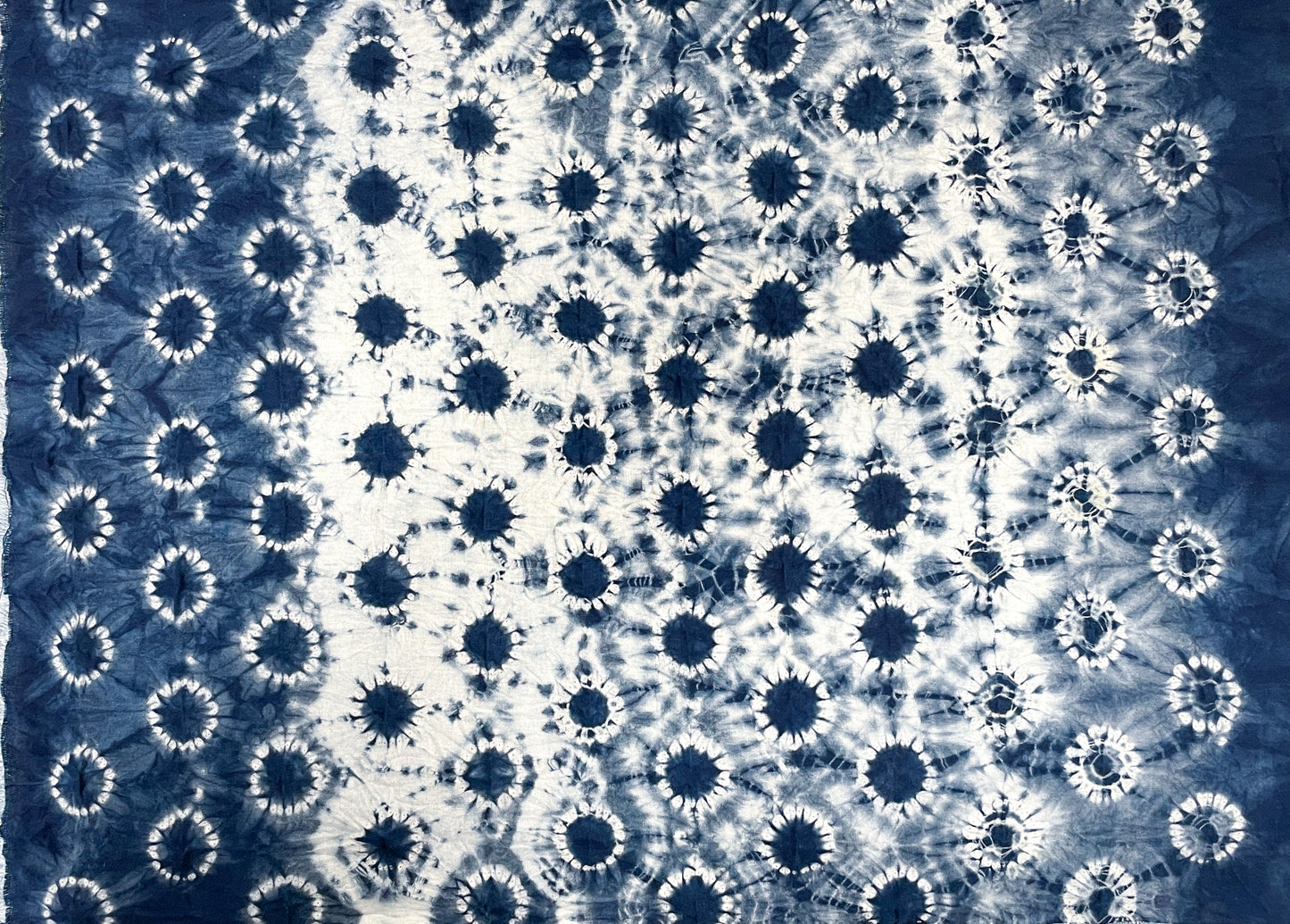 The Stitch Resist for Shibori by Creative Spark features blue and white tie-dye with dense circular patterns at the center, fading to sparser circles at the edges, showcasing traditional shibori stitch resist techniques.