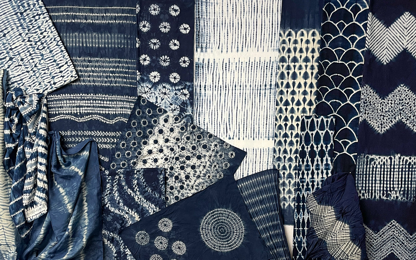 Creative Spark's "Stitch Resist for Shibori" showcases indigo-dyed textiles with intricate patterns—stripes, circles, florals, zigzags, and geometrics—in deep blue and white, created using shibori stitch techniques.