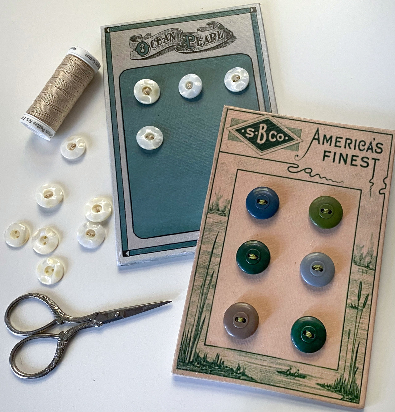 The Creative Spark Pearl Button Primer features two vintage button cards—one with white buttons, one colorful—displayed with a thread spool, loose buttons, and metal scissors, ideal for inspiring your next vintage notions project.