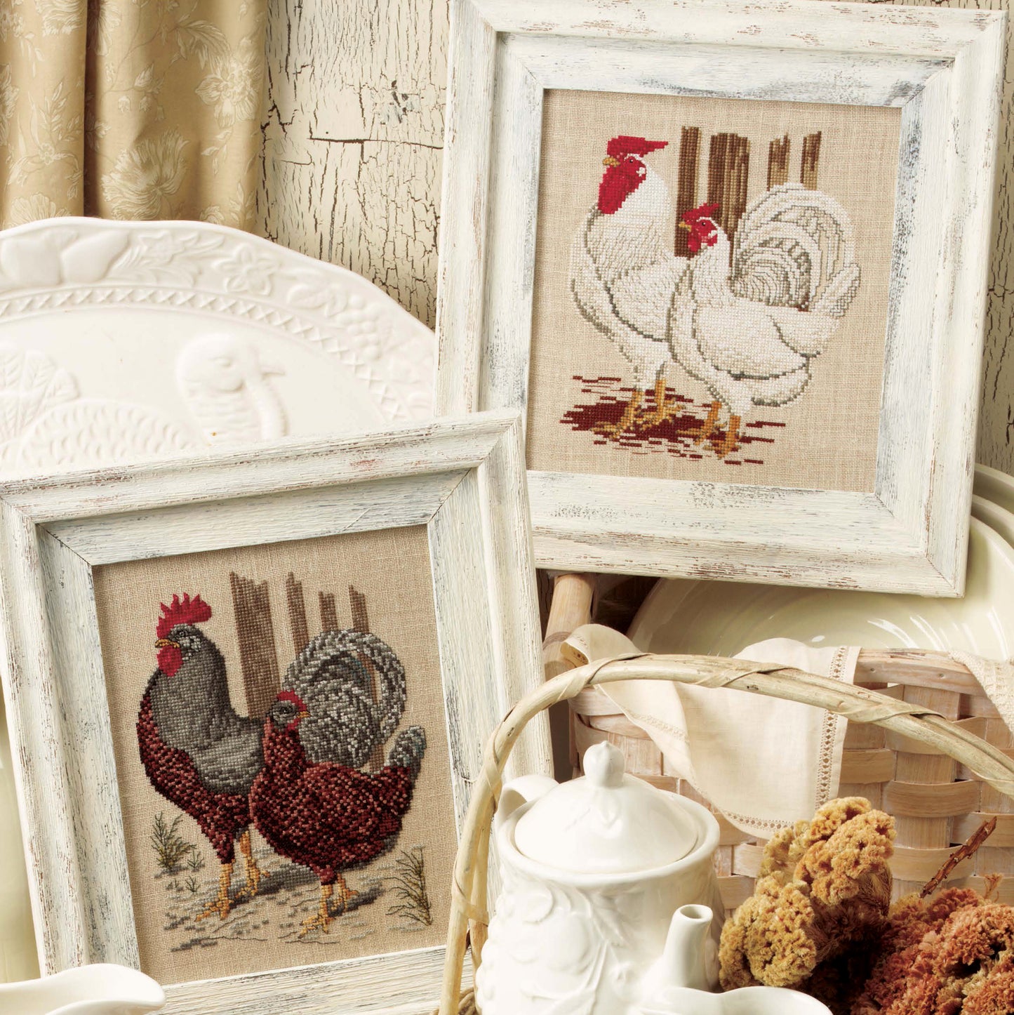 Leisure Arts’ “Fresh Approach” features two framed barnyard cross stitch artworks—rooster and hen designs—displayed on a rustic surface with white dishware, a teapot, and baked goods for a cozy farmhouse feel.