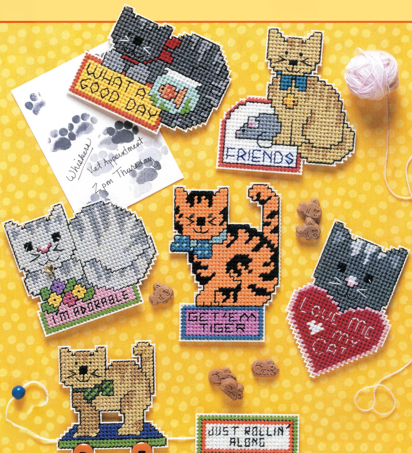 Leisure Arts Cat Chat Magnets feature colorful cross-stitched cat designs on a yellow polka-dot background with fun sayings, paw prints, yarn, and fish treats—playful feline kitchen decor and a delightful gift for cat lovers.