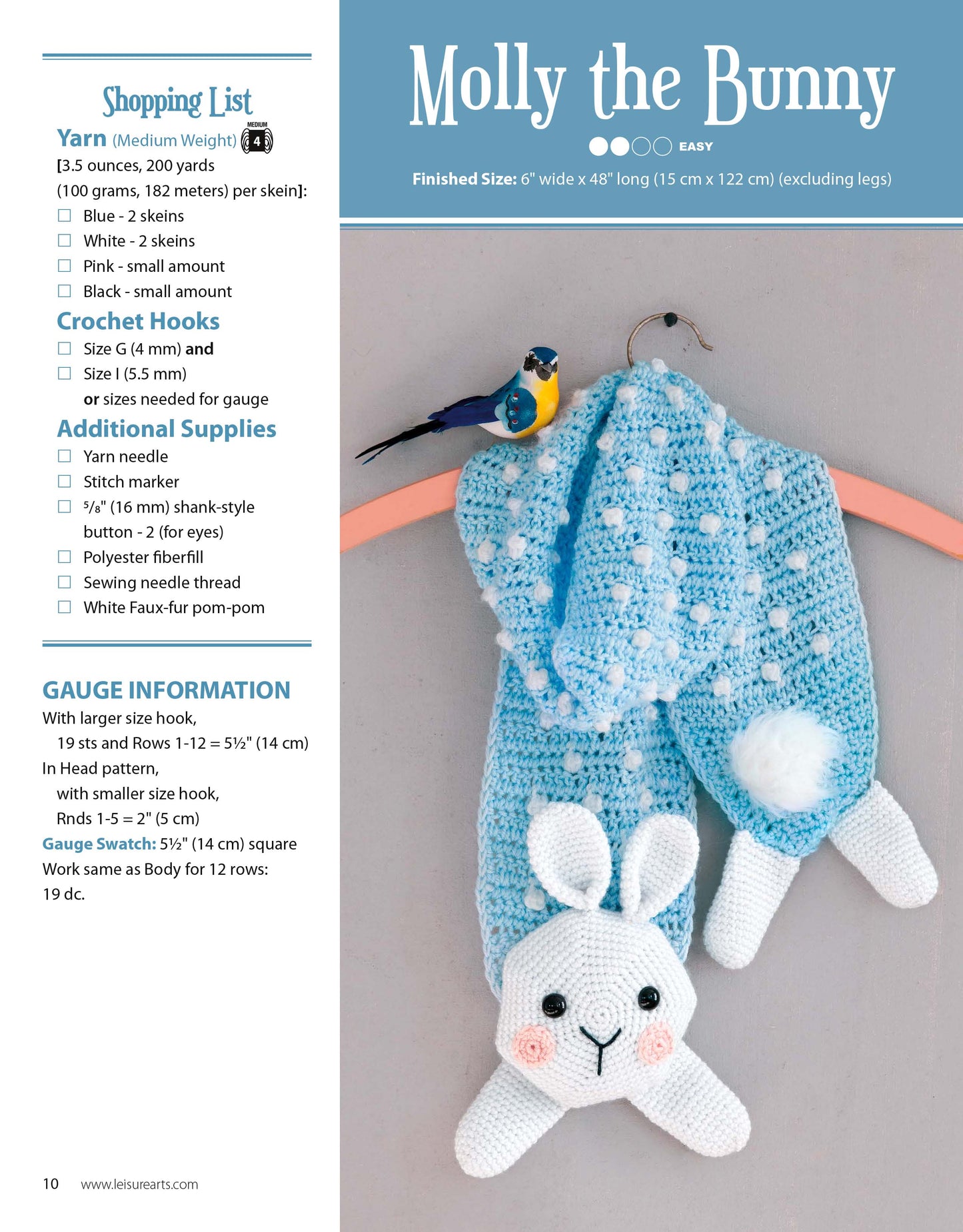 A blue crocheted bunny lovey with a white head and paws from Leisure Arts’ Amigurumi Animal Scarves rests on a pink background, with a crochet hook and yarn beside it. Instructions and supplies are shown on the left for easy scarf projects.