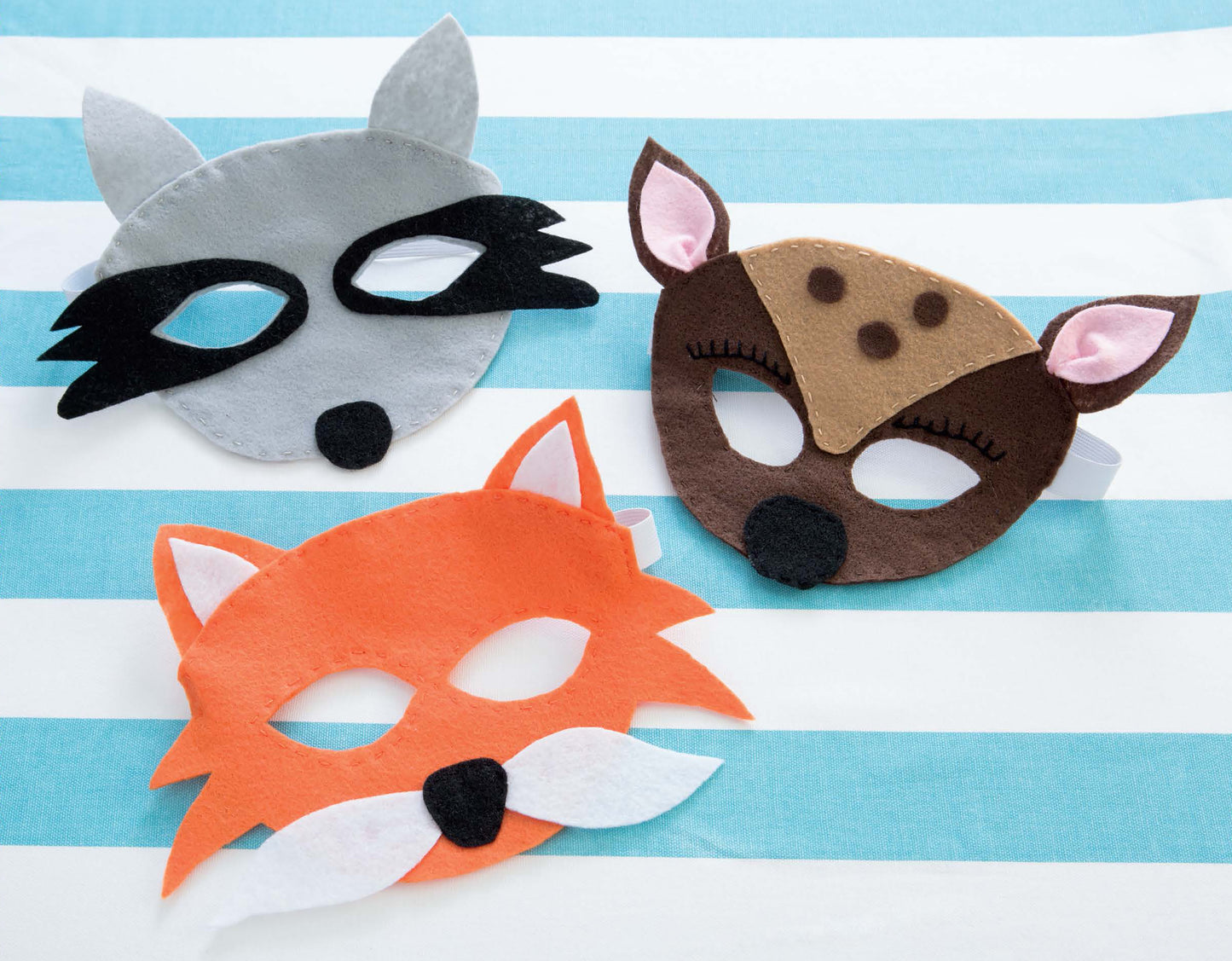 Leisure Arts Kids' Felt Cuties features three animal masks—a gray raccoon, a brown deer, and an orange fox—each with cut-out eyes and simple details, perfect for kids’ craft projects or pairing with craft patterns.
