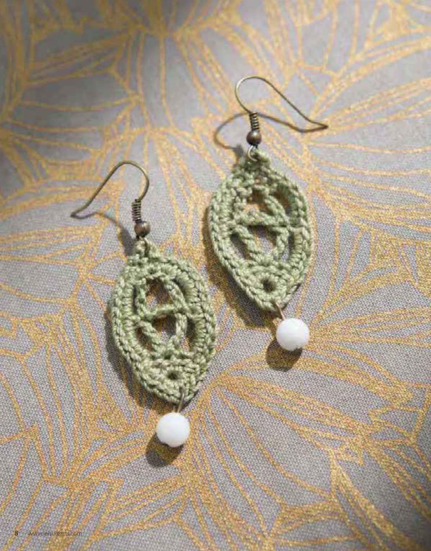 Jewelry to Crochet by Leisure Arts features leaf-shaped green crochet earrings adorned with intricate beaded designs and white beads—an elegant example of handmade crochet jewelry.