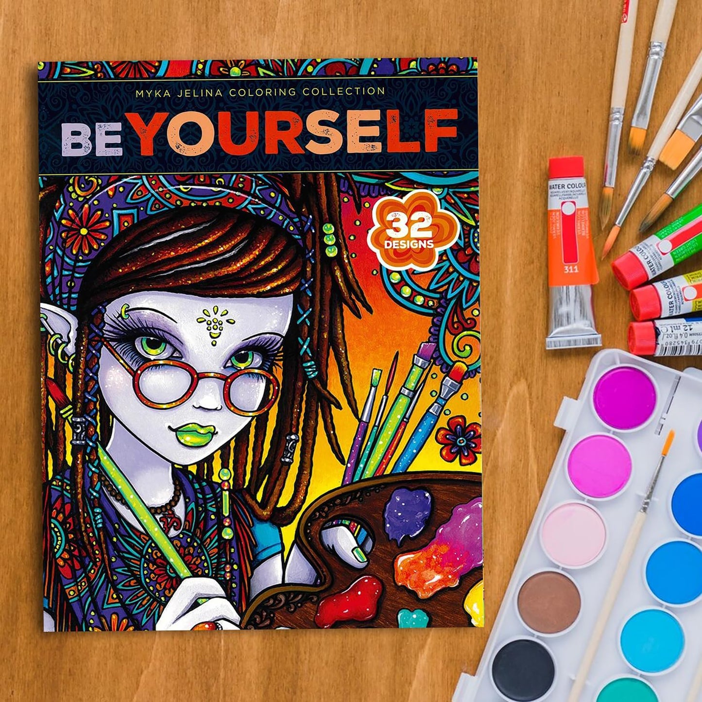 The Be Yourself Coloring Book—32 Designs from the Myka Jelina Coloring Collection by Leisure Arts features a colorful cover of a girl with a paint palette, surrounded by art supplies on a wooden table.