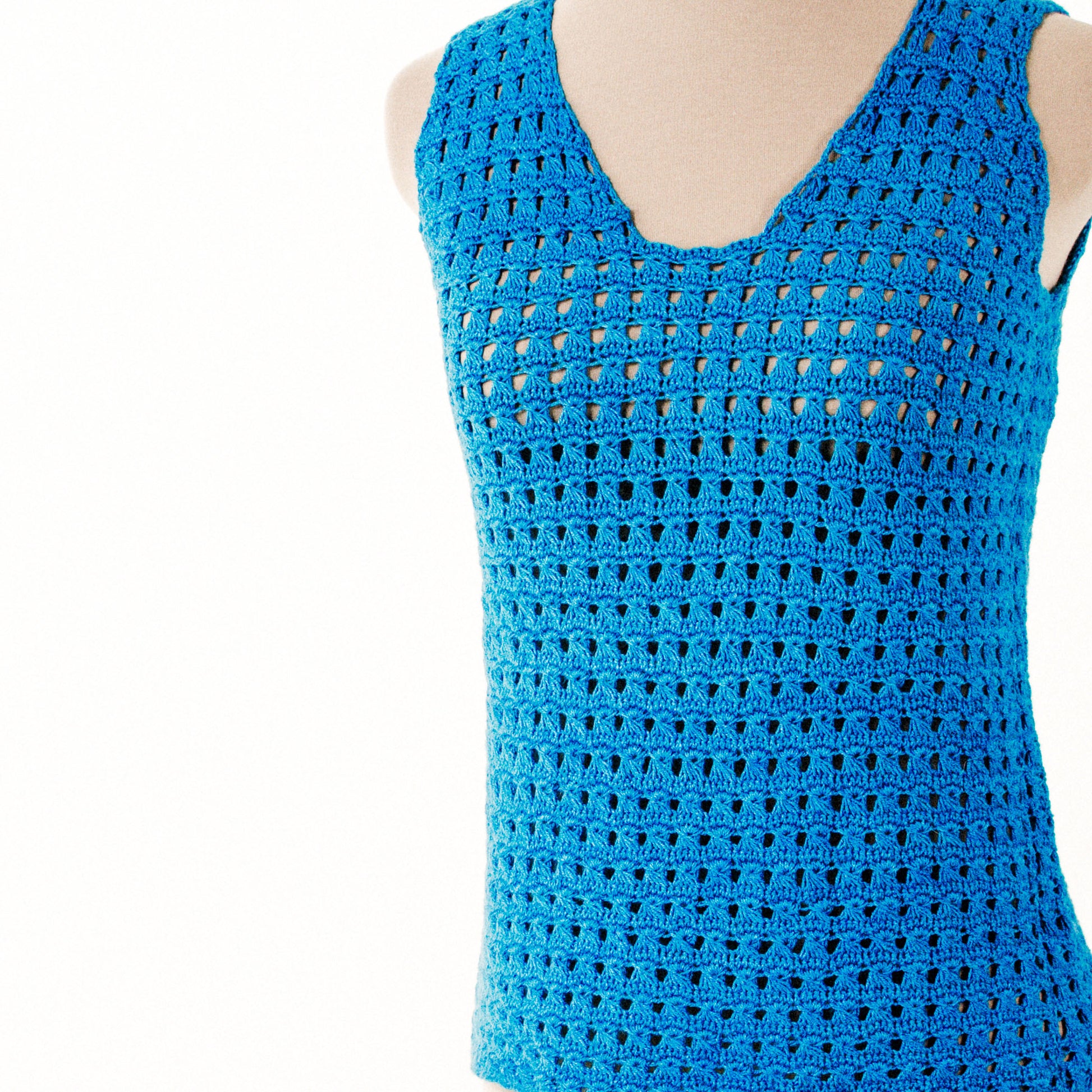 A Creative Spark Non-Stick Crochet Lace top features a sleeveless design with a blue V-neck and an intricate openwork pattern on a light background.