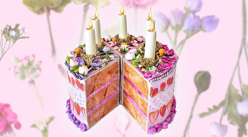 The Piece of Cake Candleholder: A DIY Tabletopper by Creative Spark is a whimsical, slice-shaped decor with four candle slots, colorful frosting, floral and fruit designs, set on a soft pastel background.