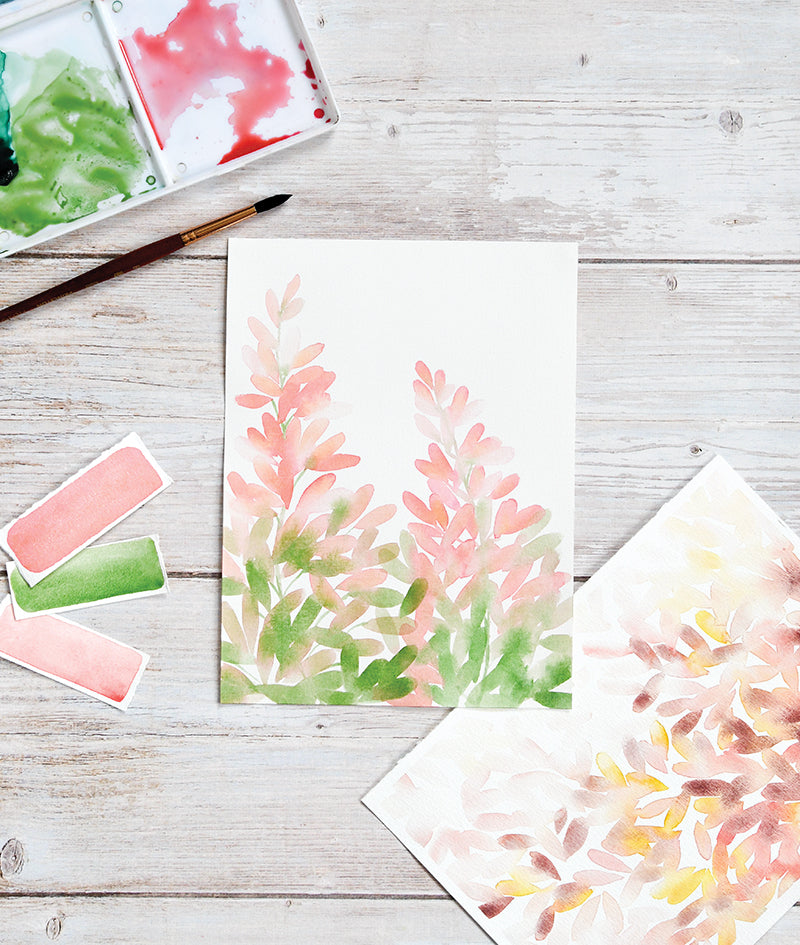 Discover "Learn to Watercolor" by Stash Books—a watercolor painting kit featuring pink and green leafy plants on white paper, plus a palette, brush, swatches, and another artwork. Perfect for practicing watercolor techniques.