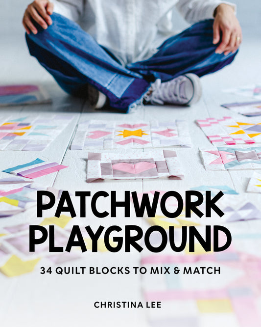 A person sits cross-legged on the floor with colorful quilt blocks. The book title "Patchwork Playground" by Stash Books is displayed boldly, capturing a playful moment for patchwork lovers.