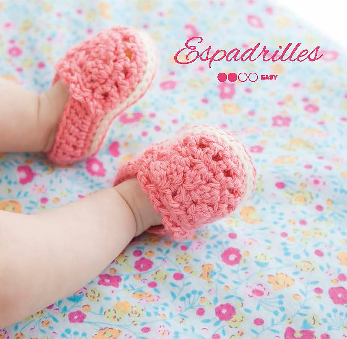 A baby wearing pink crocheted booties from "Modern Booties for Baby" by Leisure Arts lies on a colorful floral blanket. The product name and brand appear in decorative fonts in the upper right corner.