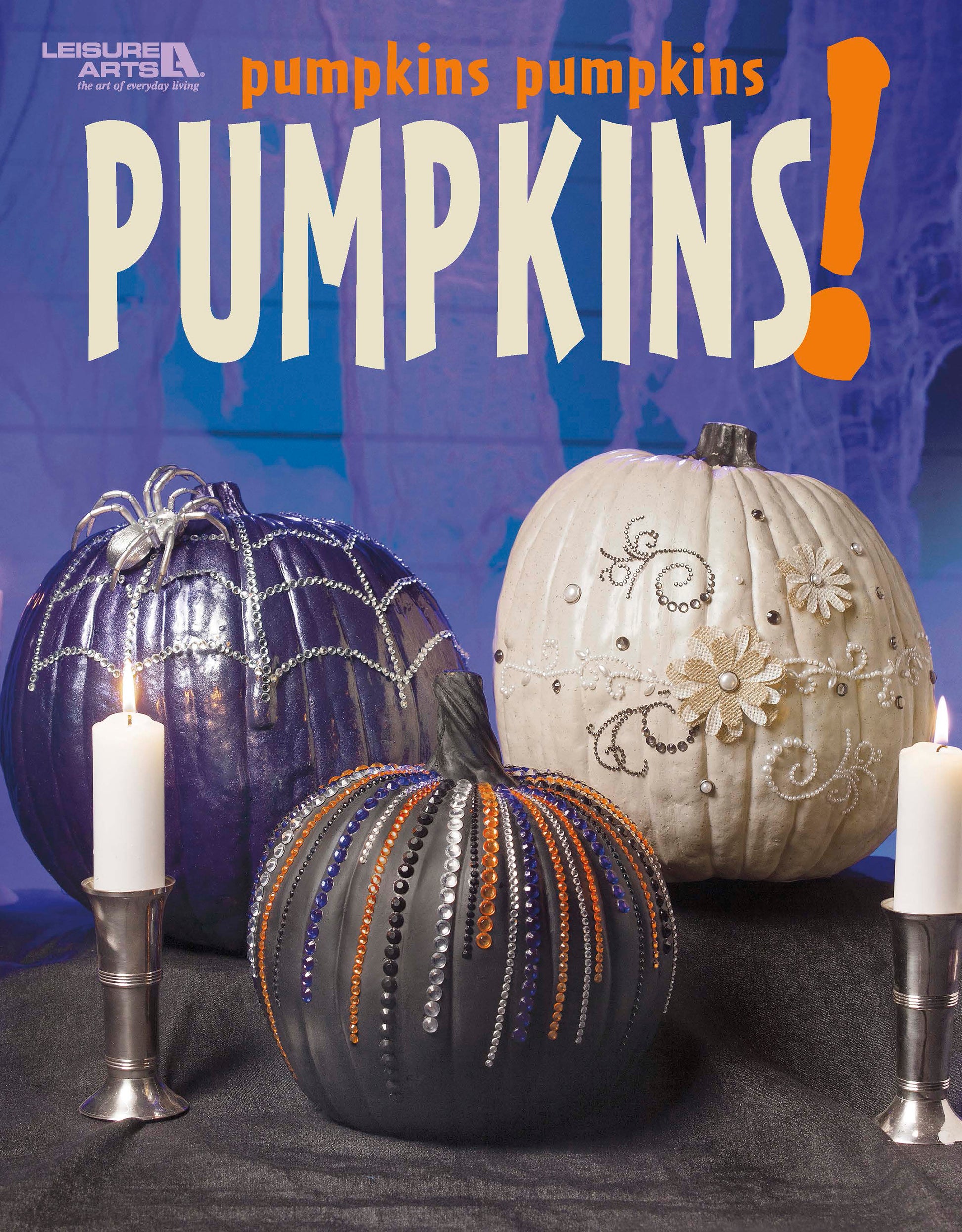 Leisure Arts’ "Pumpkins Pumpkins Pumpkins" shows three detailed faux pumpkins—purple, black, and white—with two glowing white candles against a bold purple backdrop. Above them, “pumpkins pumpkins PUMPKINS!” is written in large text.