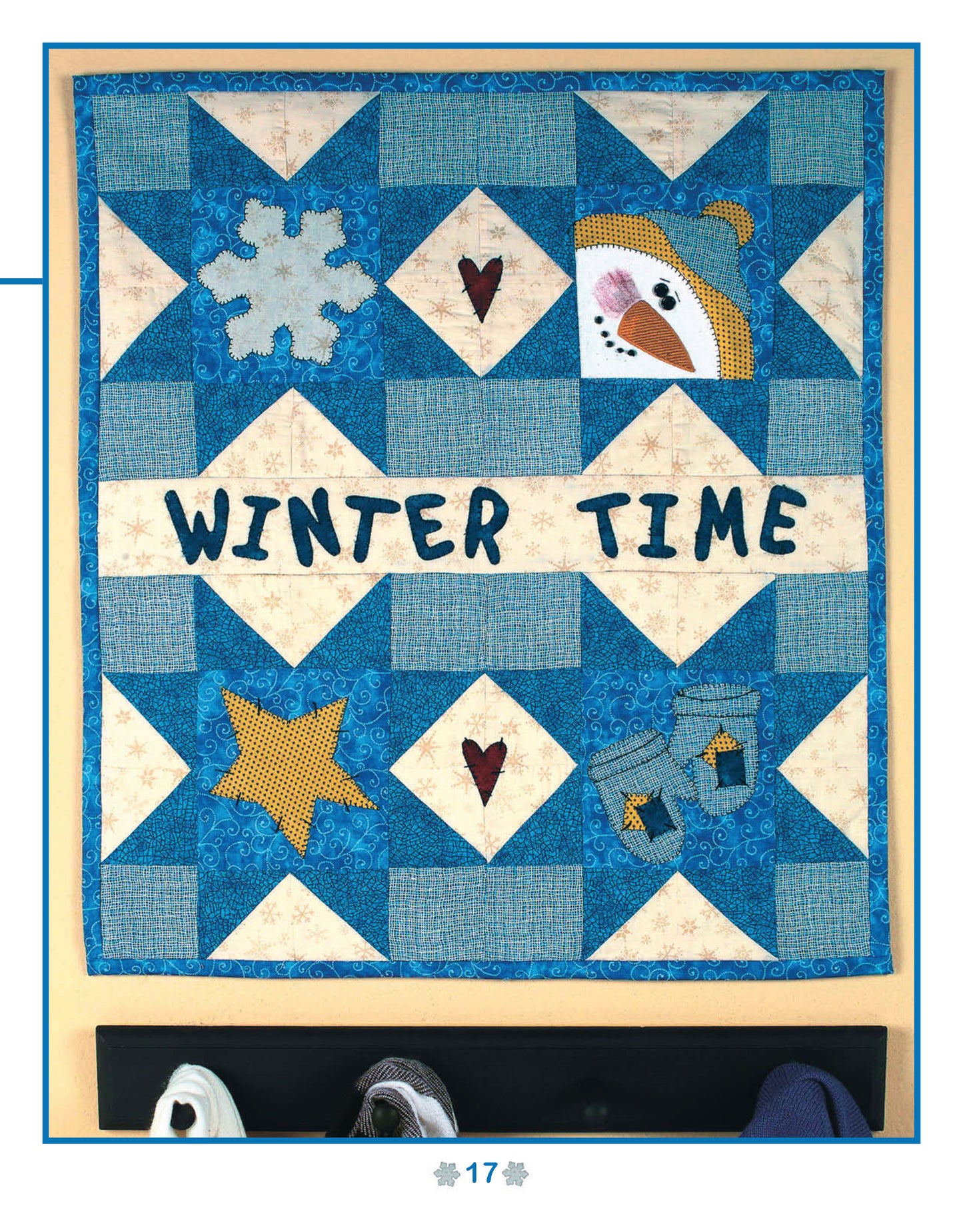 The “Quick & Easy Wall Hangings for the Seasons” digital download by Leisure Arts shows a blue and white patchwork quilt with a snowflake, star, snowman face, red hearts, musical notes, and “WINTER TIME” sewn in the center. Shoes appear at the bottom.