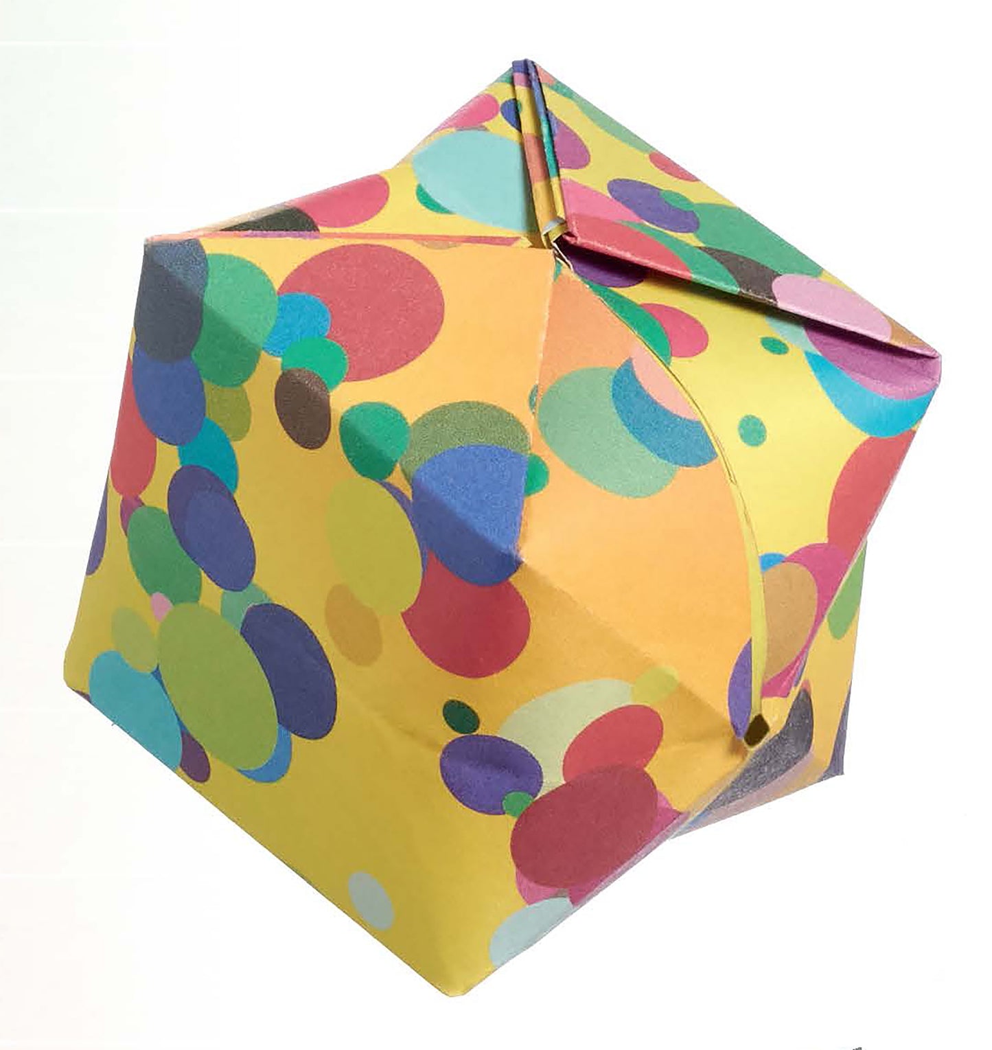 Origami Fun by Leisure Arts is a vibrant paper cube for origami, featuring overlapping circles in multiple colors and sizes, with a slightly open corner, displayed on a plain white background.