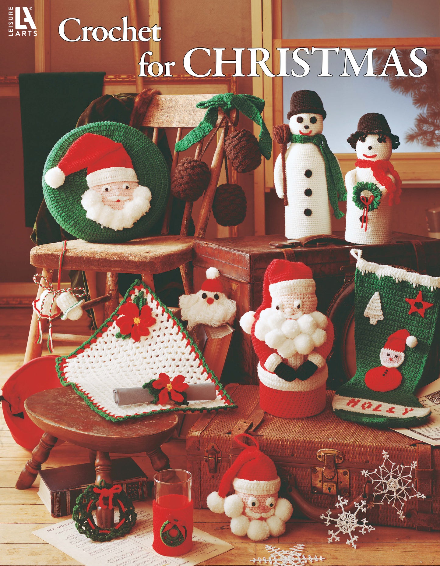 Crochet for Christmas by Leisure Arts showcases crochet Santa figures, snowmen, stockings, wreaths, an afghan, and ornaments in worsted weight yarn—festive home decor arranged with a wooden chair and table for cozy holiday charm.