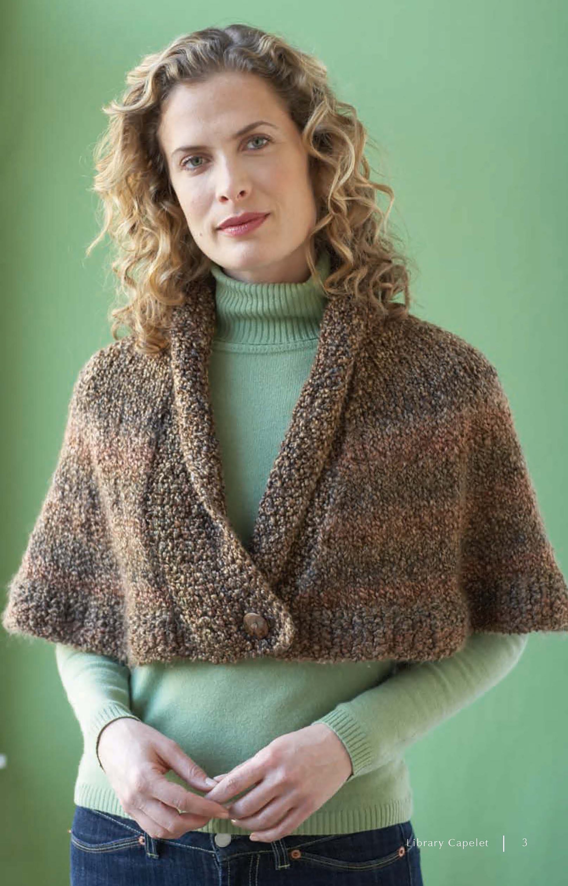 A woman with curly hair models a brown knitted capelet from Cozy Cover-Ups—4 Crochet & 2 Knit Designs Created with Lion Brand Homespun by Leisure Arts, layered over a light green turtleneck and set against a green background.