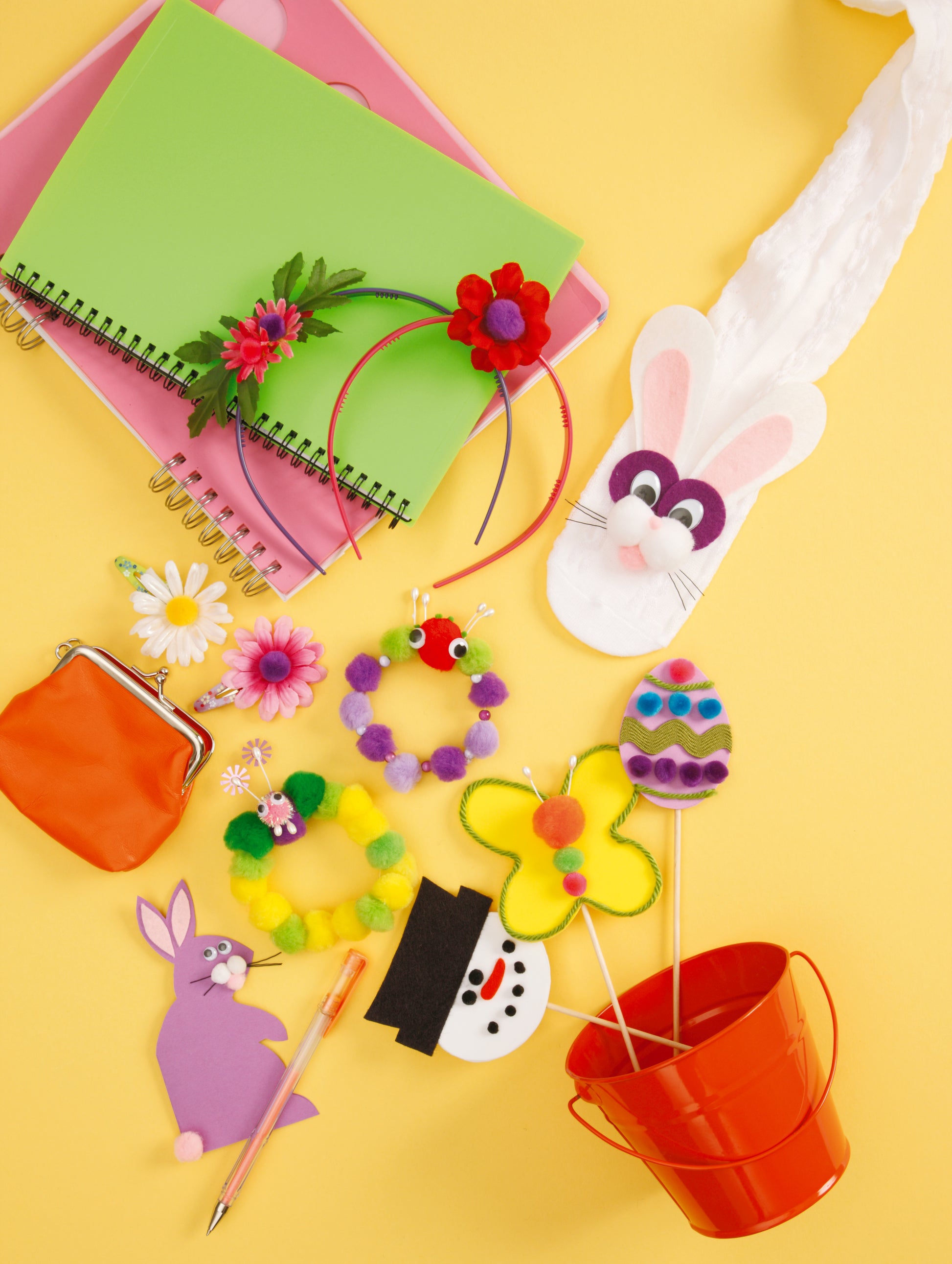 Bright flat lay of Leisure Arts Pompom Crafts on a yellow background, with flower and animal crafts, notebooks, felt bunny and egg decorations—perfect for fun craft projects for kids.