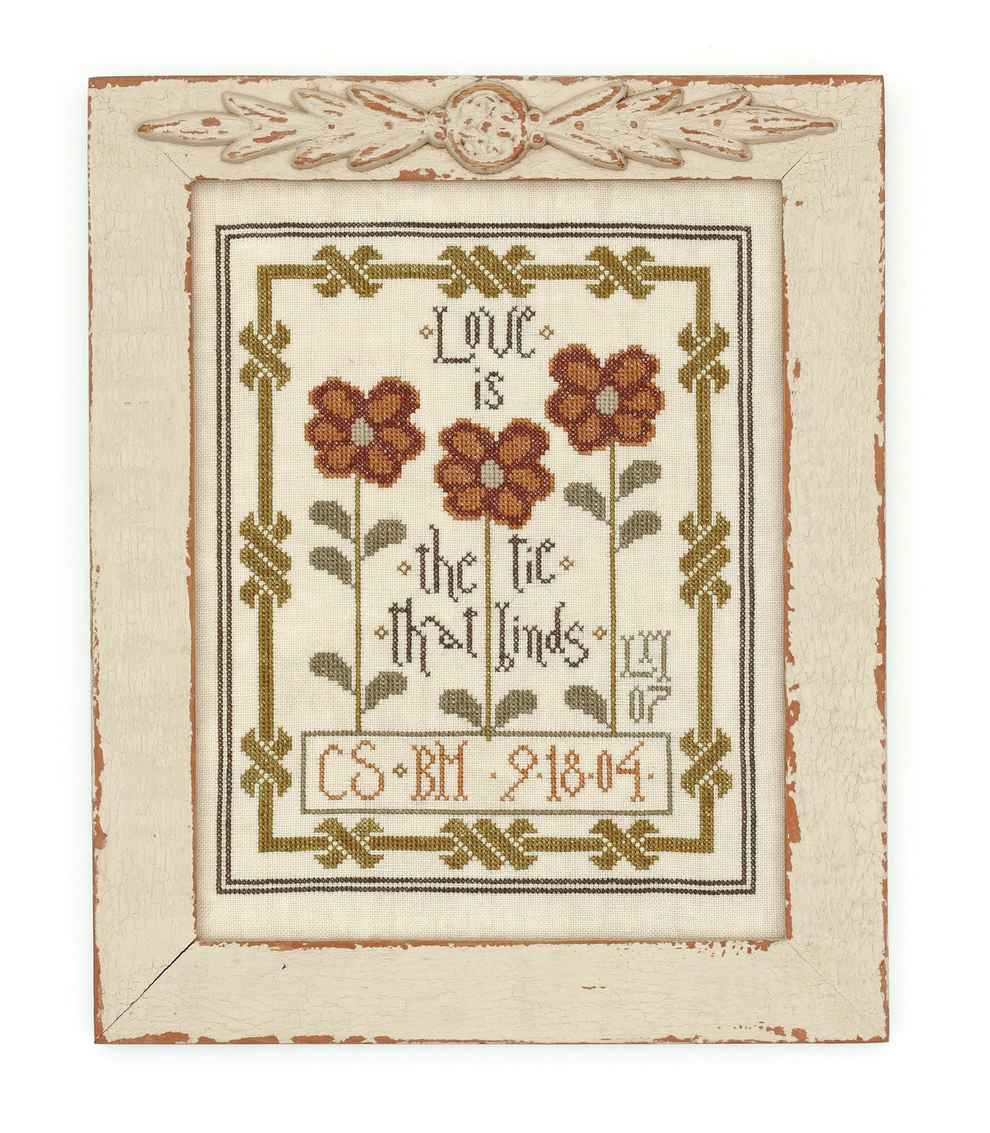 Leisure Arts' "Words To Stitch By" is a framed cross-stitch sampler with three red flowers, green leaves, and "Love is the tie that binds." Initials and 9-18-04 are at the bottom, all in a rustic wooden frame with classic patterns.