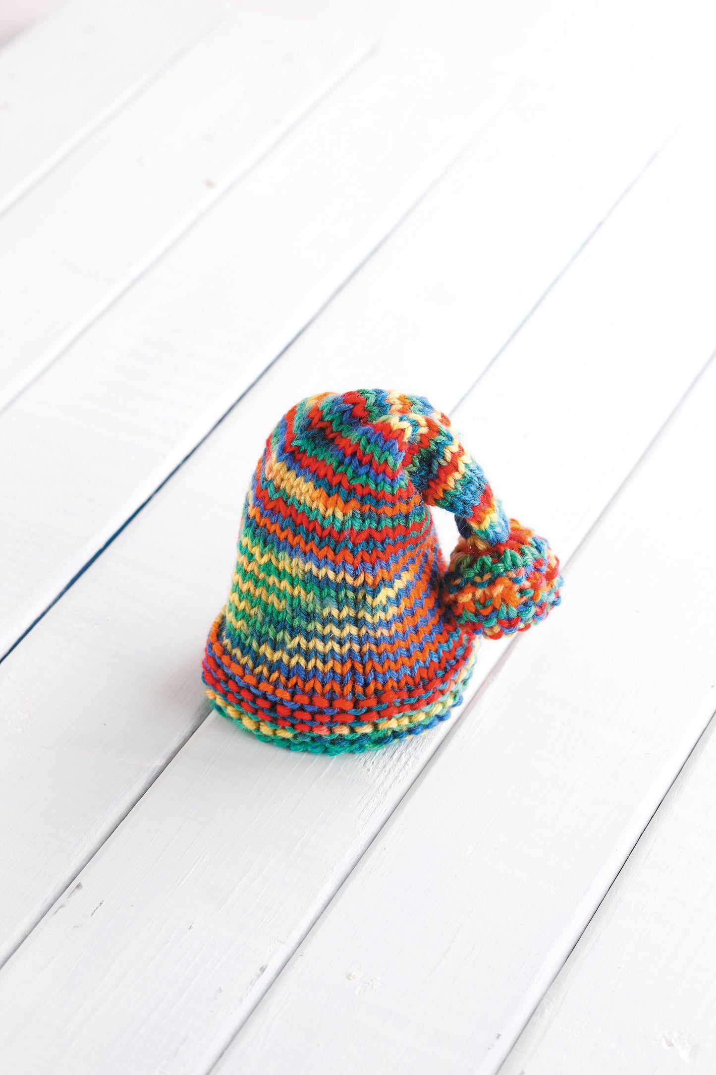 The Leisure Arts "Warm Hats for Wee Noggins" features a vibrant, pointed baby hat with a pom-pom and rainbow stripes—ideal inspiration for anyone seeking knit baby hats or newborn knitting patterns.