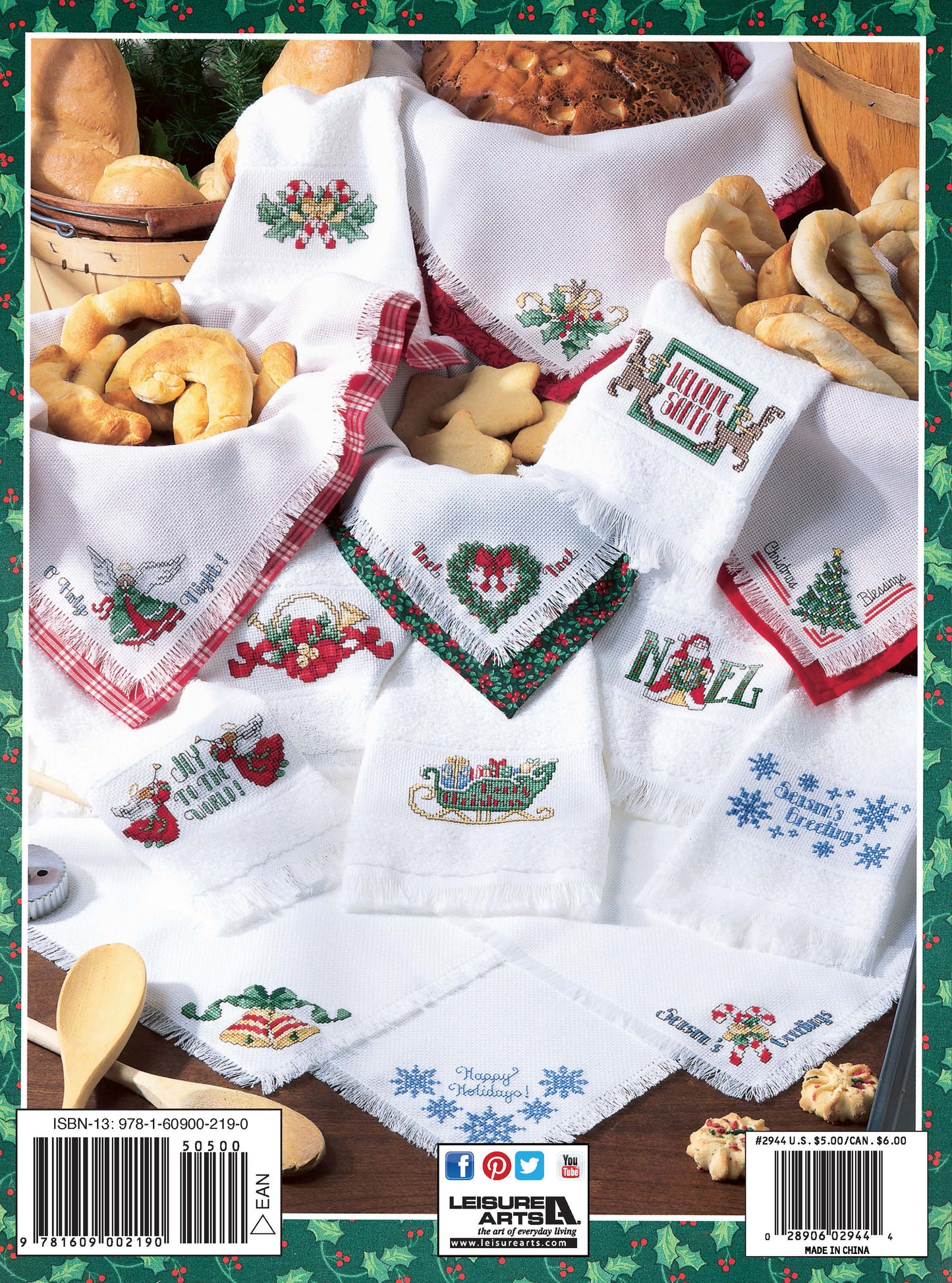 Back cover of Leisure Arts' "Christmas Towels & Bread Cloths" features beginner holiday embroidery patterns—angels, sleighs, and greetings—on white kitchen towels, displayed with festive breads and cookies for charming Christmas decor.