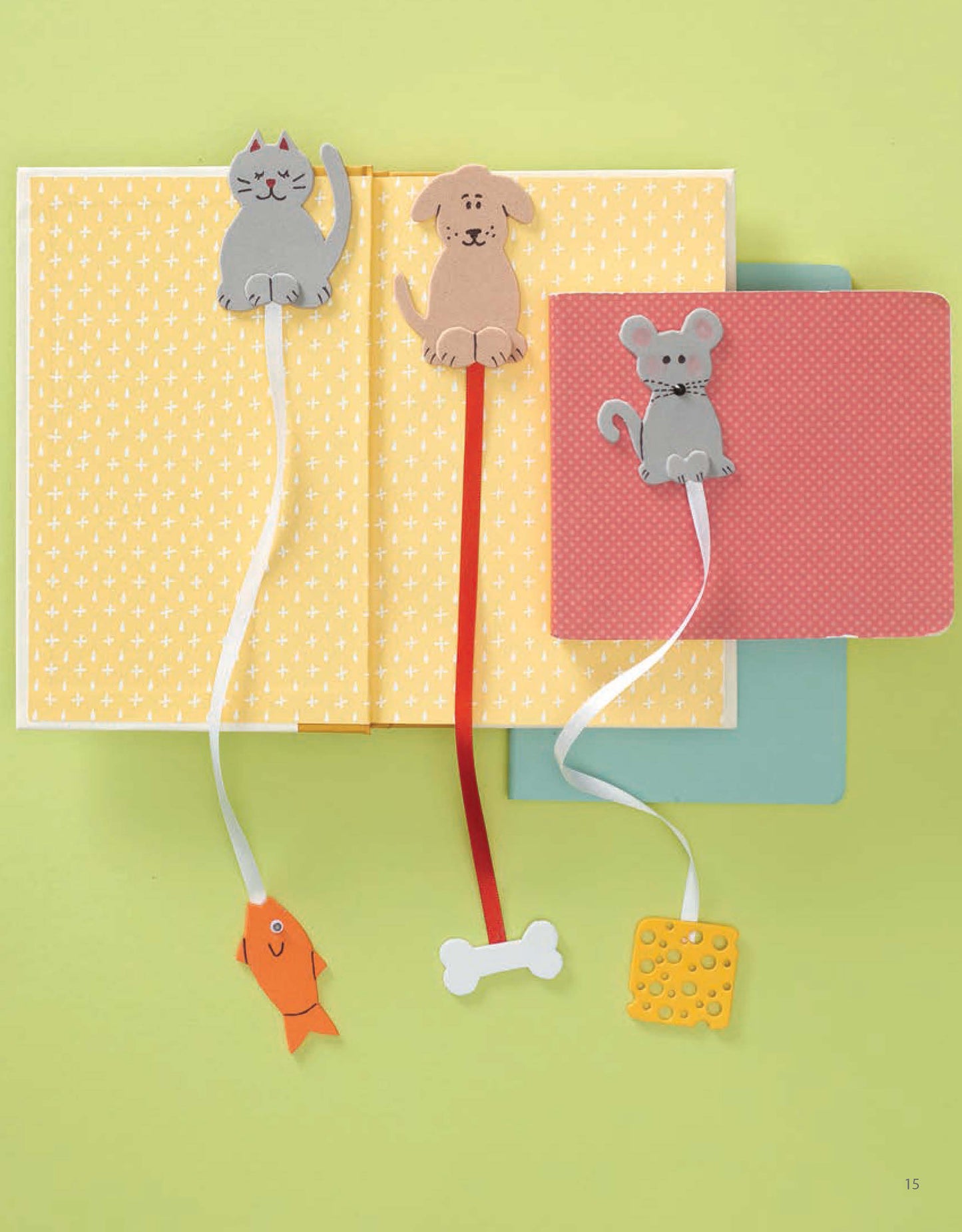 Leisure Arts Craft Foam Favorites: three ribbon bookmarks with felt toppers—a cat with fish, dog with bone, and mouse with cheese—are great for kids crafts or DIY decor, displayed on colorful notebooks and a yellow-patterned book.