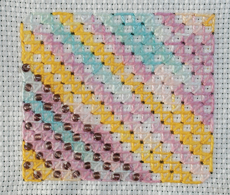 A close-up of pastel striped needlepoint on white canvas, from Creative Stitches for Contemporary Embroidery, Volume 2 by C&T Publishing—a glossy, inspiring example for any embroidery or hand stitching enthusiast.
