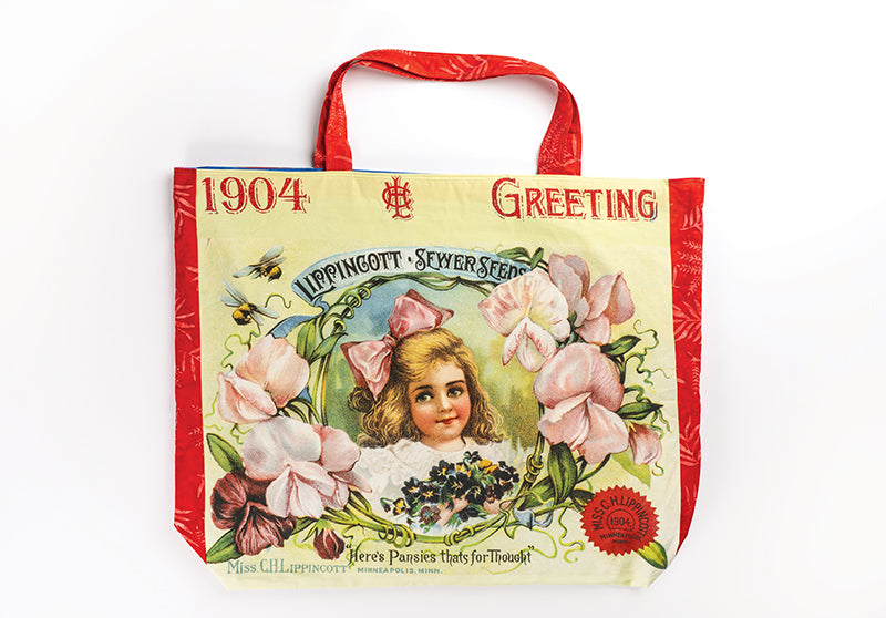 The Quilt Panel Magic tote by C&T Publishing has red handles and trim with a vintage floral design, a girl’s portrait, and “1904 Greeting” and “Lippincott’s Sewer Seed”—ideal for carrying step-by-step quilt instructions or panel quilts.