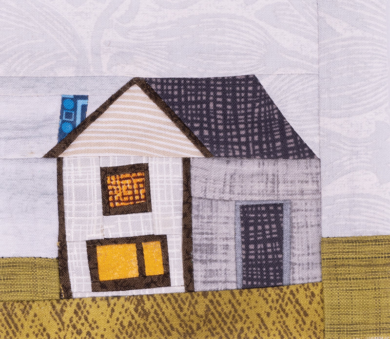 The "Quilt Small, Dream Big" fabric patch by C&T Publishing features a house with a lit window, dark roof, and green-yellow yard in patterned fabrics—ideal for practicing miniature piecing or beginner quilting techniques.