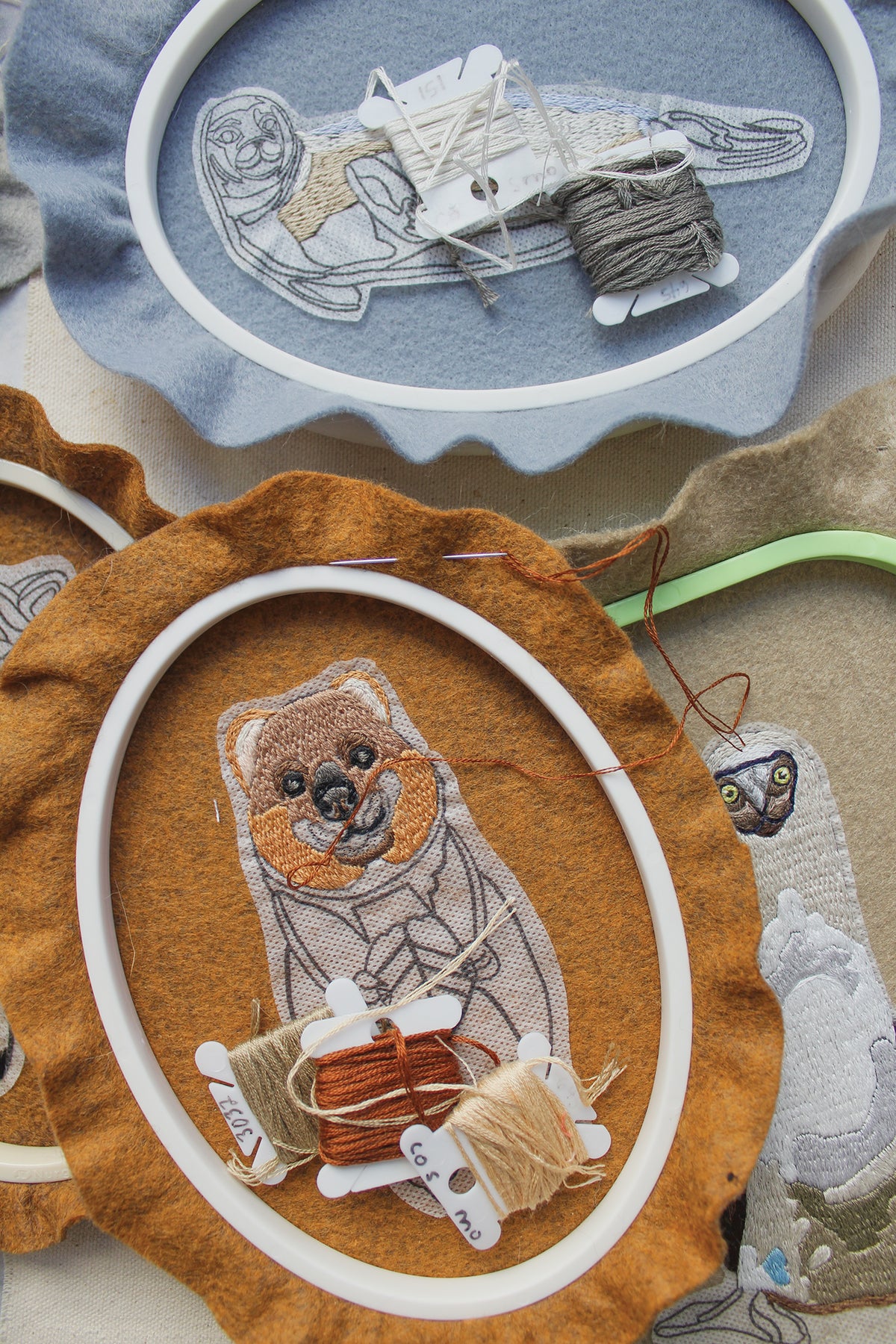 Wild & Wearable Animal Embroidery kit featuring three hoops with felt animal embroidery, bobbins of thread, and needles.