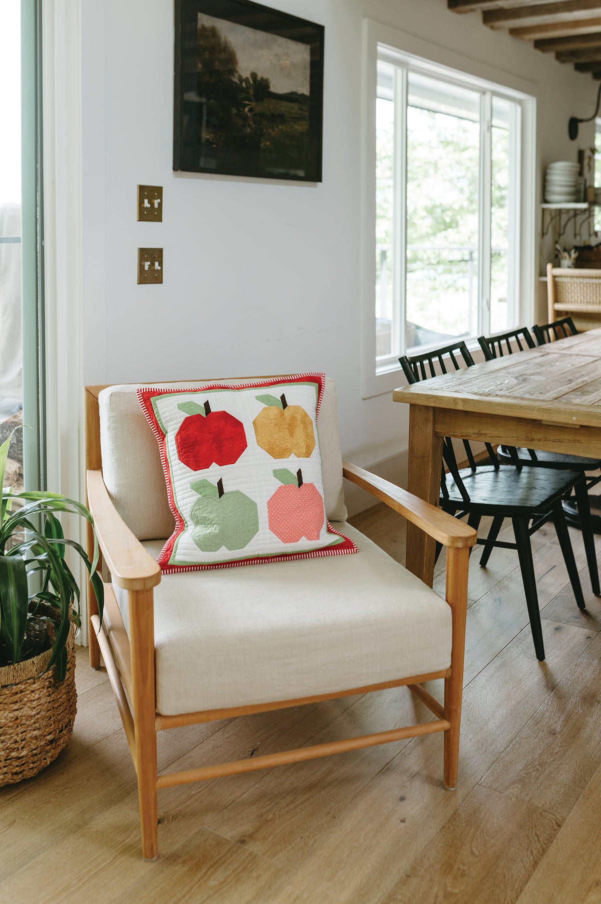 Sew a Pillow a Month quilted throw pillow featuring a four-apple grid design on an armchair, perfect for seasonal decorating.