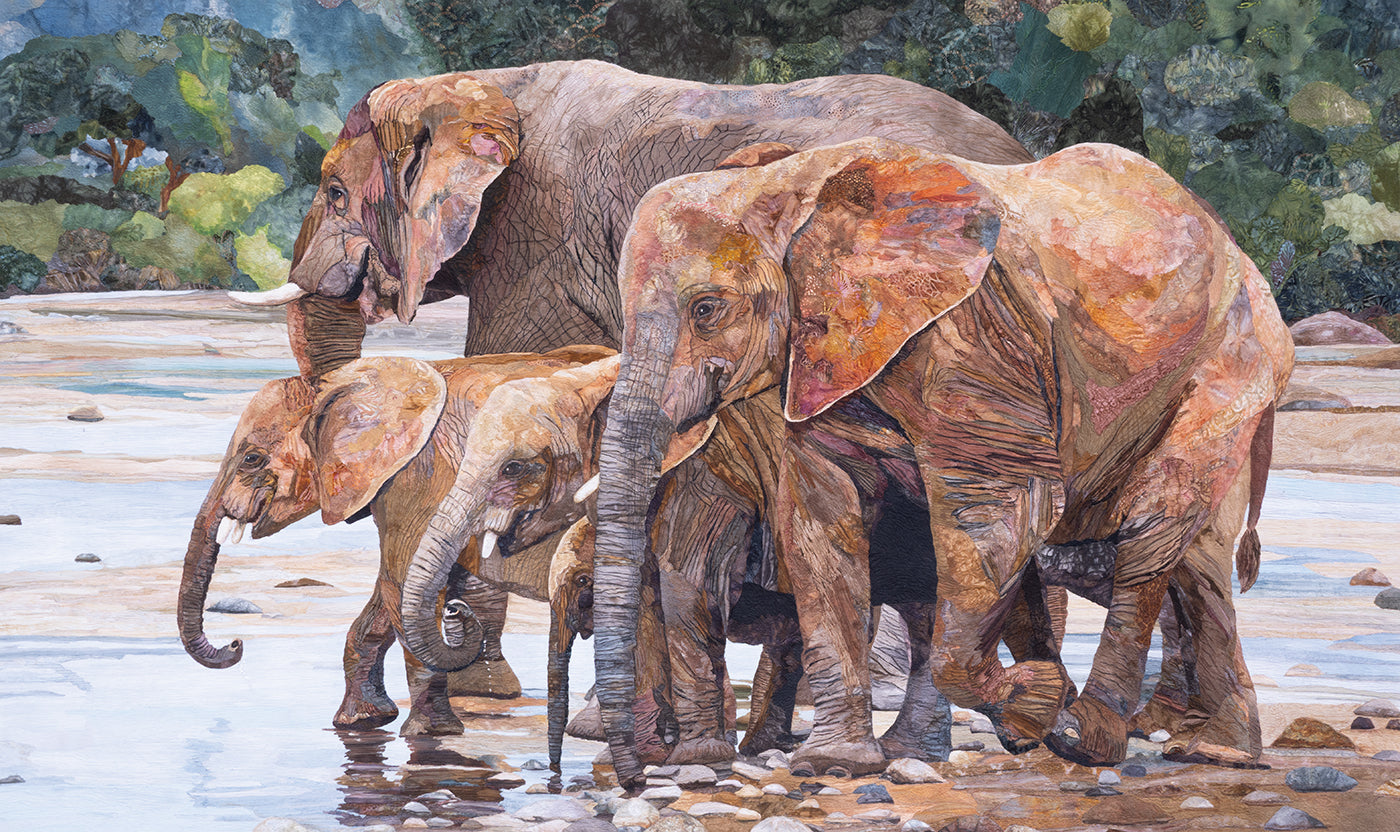 A group of four elephants, including two adults and two calves, stand close together at the edge of a shallow waterhole in a lush green landscape—their forms and textures captured with stunning detail inspired by *Quilted Realism* from C&T Publishing, reminiscent of an art quilt.