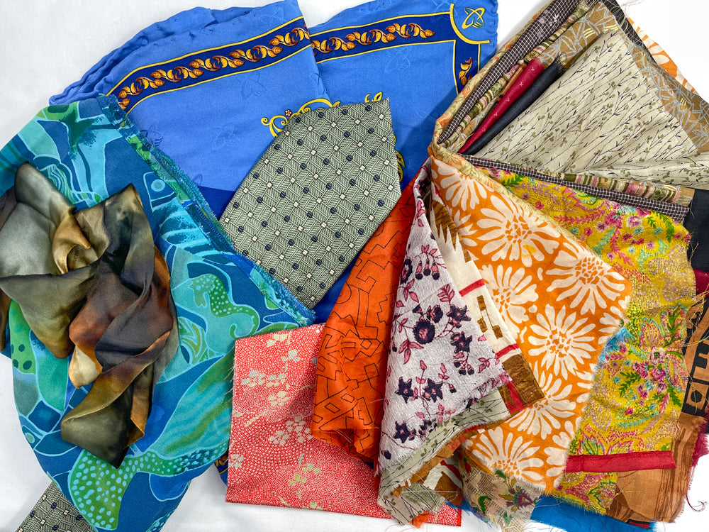 A vibrant collection of patterned fabric pieces—in shades of blue, orange, green, and floral prints—ideal for projects from Creative Spark’s Silk Art Quilts Made Simple with Stitch Library, perfect for silk art quilts or hand embroidery embellishments, displayed on a white background.