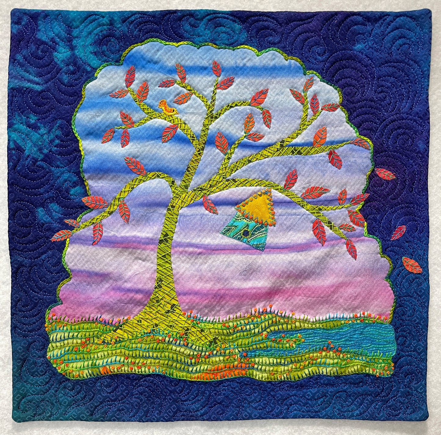 The Creative Spark "Wrong Handle Silk Art Quilts Made Simple" features a vibrant wall hanging with a large orange-leaved tree, tiny house on a branch, grassy hill, swirling purple-blue sky, and elegant embroidered quilt patterns.