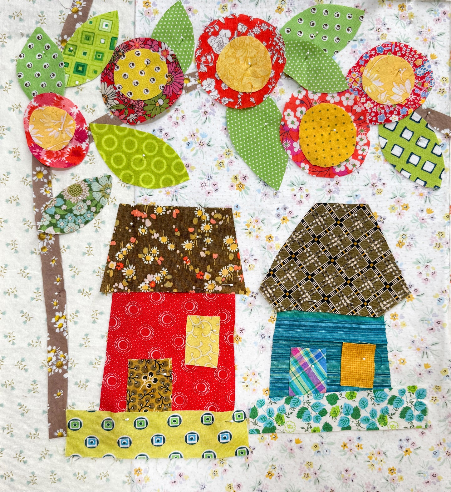 Buttonwood Village: Build an Adventure Block of the Month by Creative Spark features a vibrant fabric collage with whimsical houses, leafy trees, and bright flowers—ideal inspiration for your next appliqué BOM project.