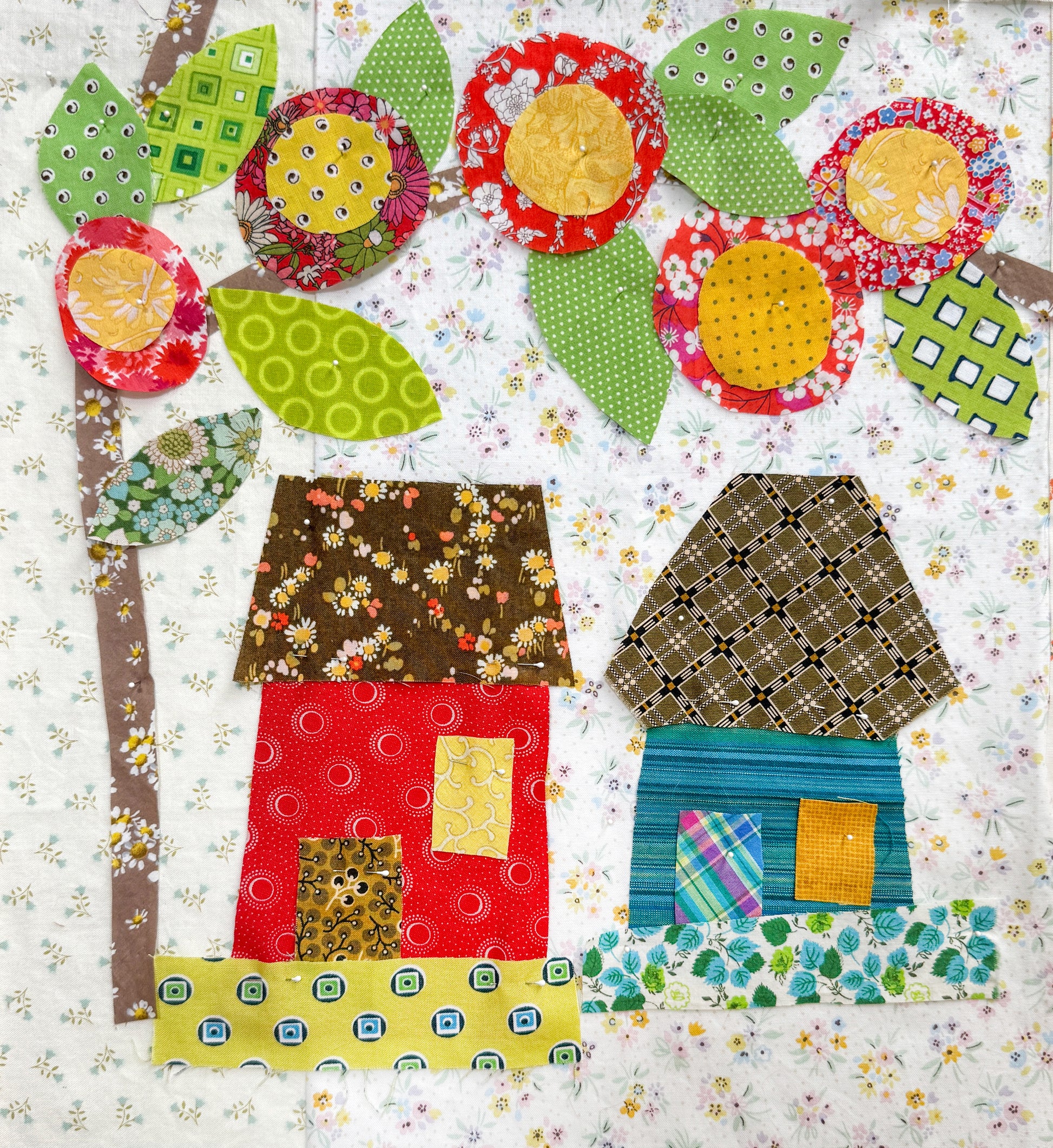 Buttonwood Village: Build an Adventure Block of the Month by Creative Spark features a vibrant fabric collage with whimsical houses, leafy trees, and bright flowers—ideal inspiration for your next appliqué BOM project.