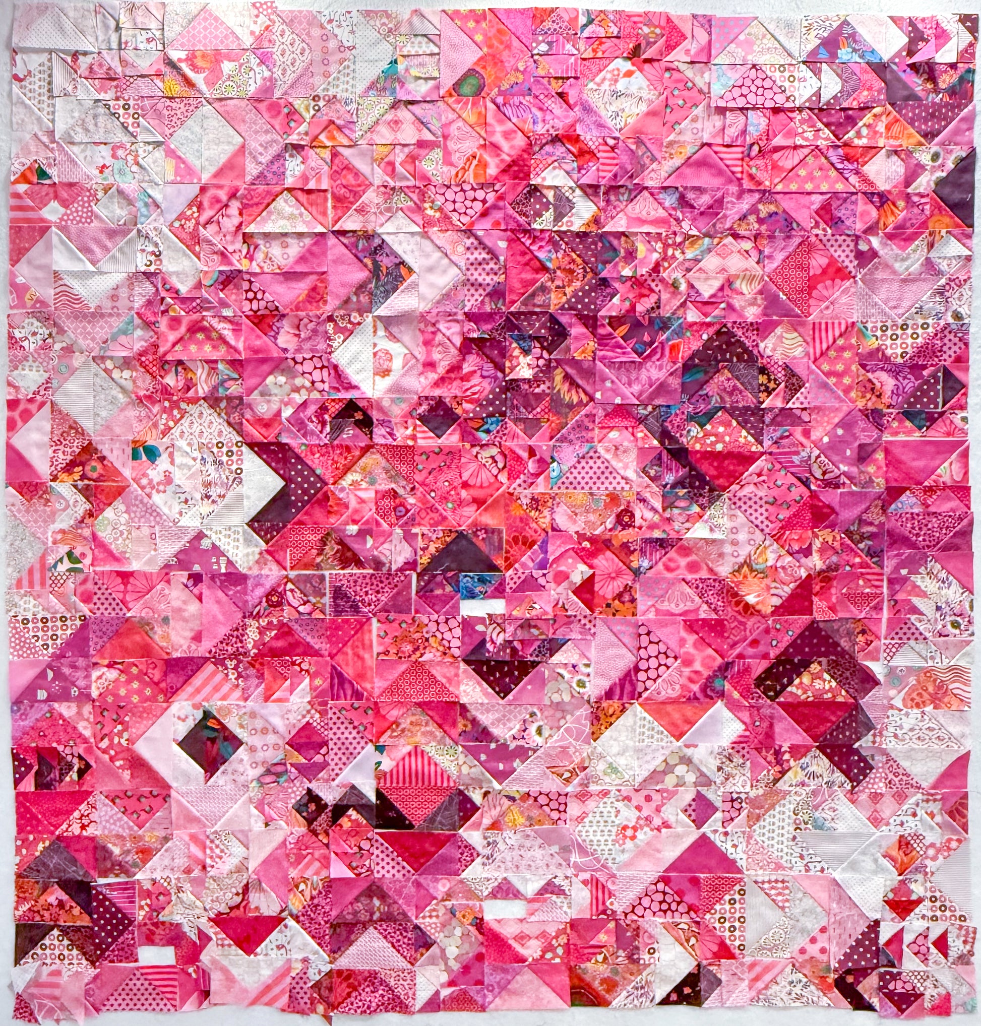 The Misunderstood Quilt by Creative Spark blends color, value, and precision in a vibrant patchwork of pinks with white, purple, and red accents, featuring expertly pieced geometric squares and triangles.