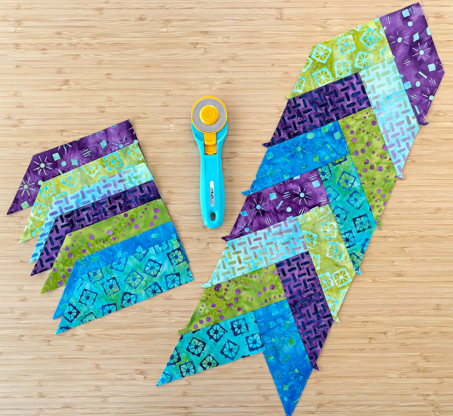 Creative Spark’s Patchwork Braids 101 Basics features blue, green, and purple fabric strips in chevron patterns on wood, with a turquoise rotary cutter displayed between patchwork braid sections.