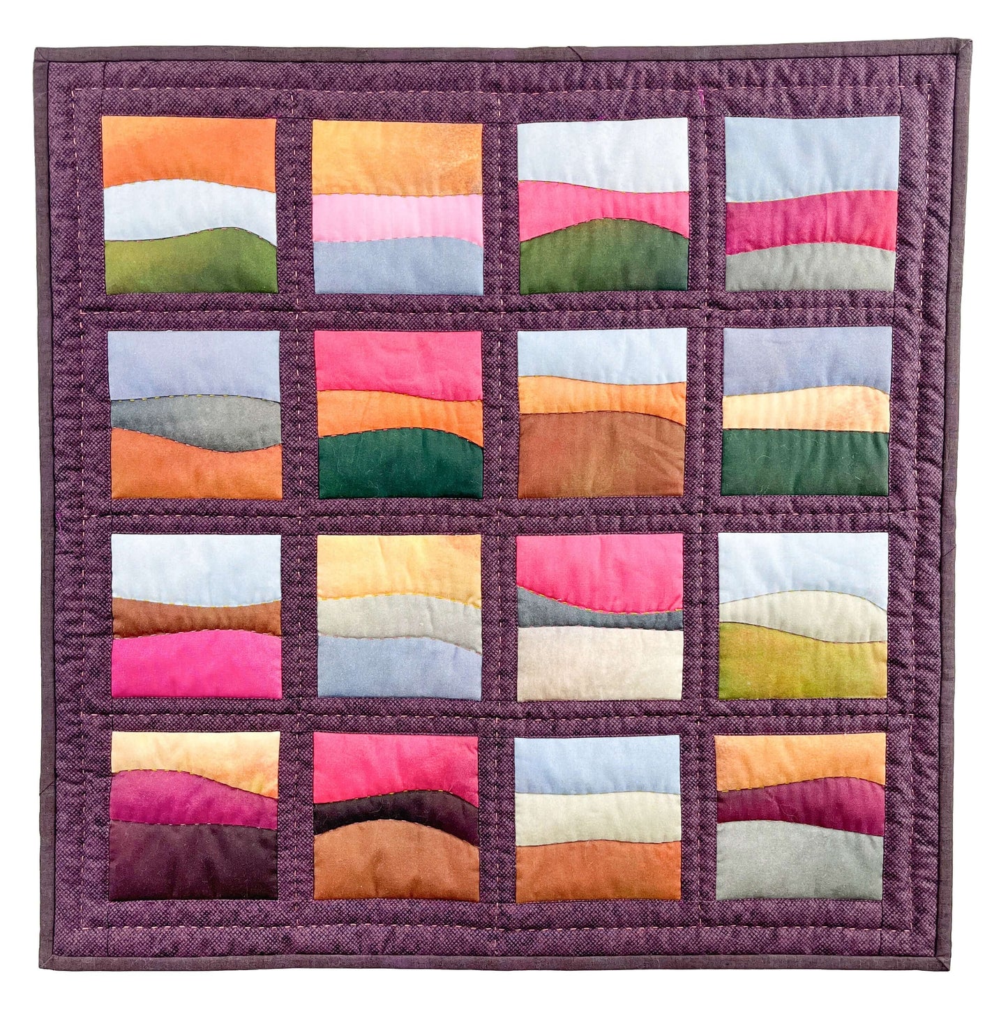 The "Landscapes as Building Blocks: Quilt the Places You Love with Easy Improv" kit by Creative Spark features 16 vibrant, wavy landscape blocks in pink, orange, green, brown, purple, and blue—ideal for scenic quilt enthusiasts.