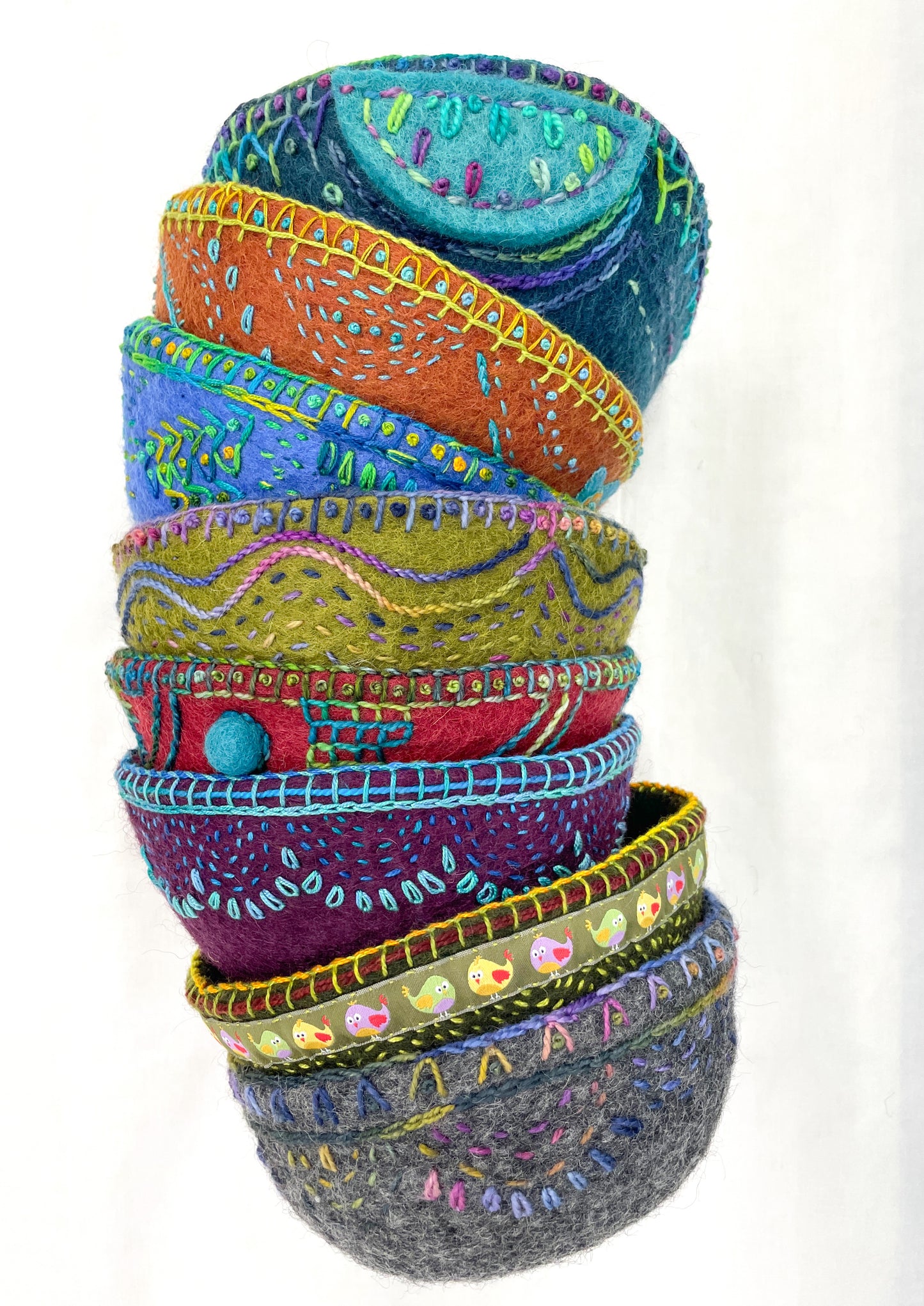 Creative Spark’s “Embroidery in the Round: Learn Stitching & Embellishment on Felt Bowls” features colorful, hand-stitched felt bowls with vibrant embroidery, appliqué patterns, and unique edging, displayed on a plain white background.